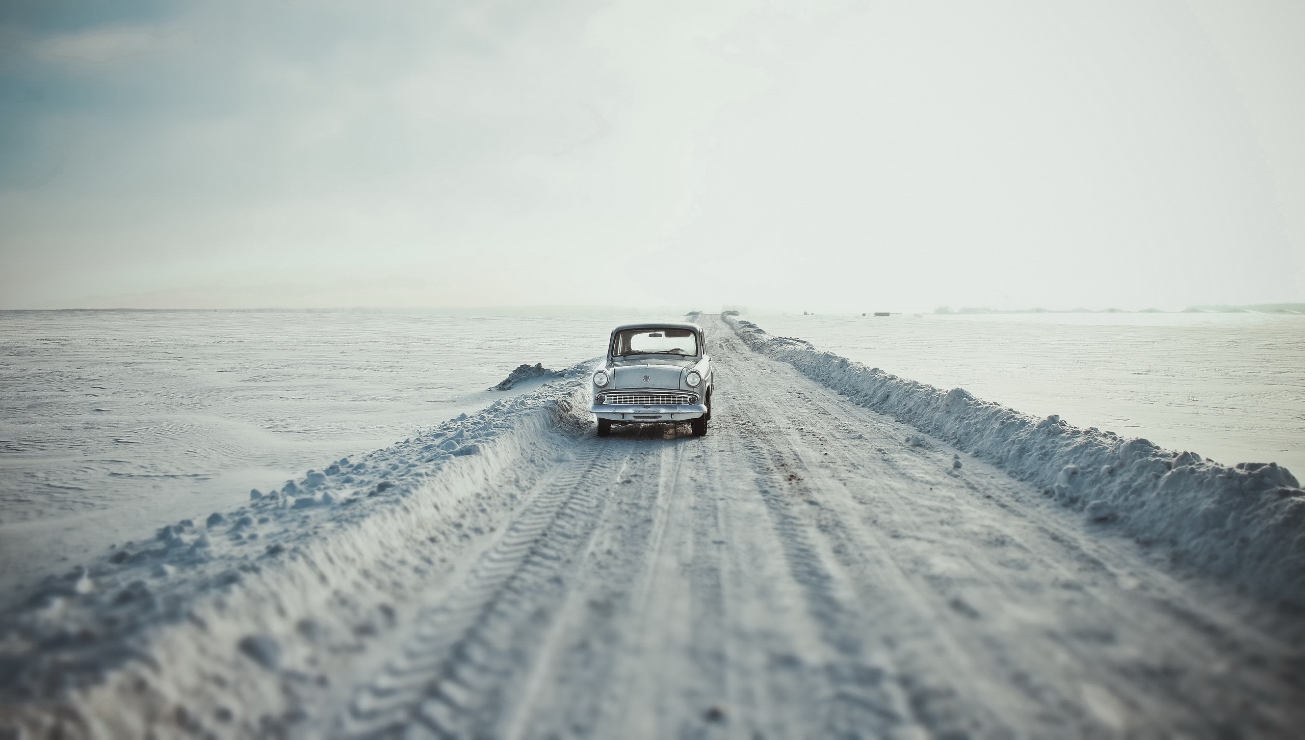 Vintage car driving on a snowy road HD Wallpaper