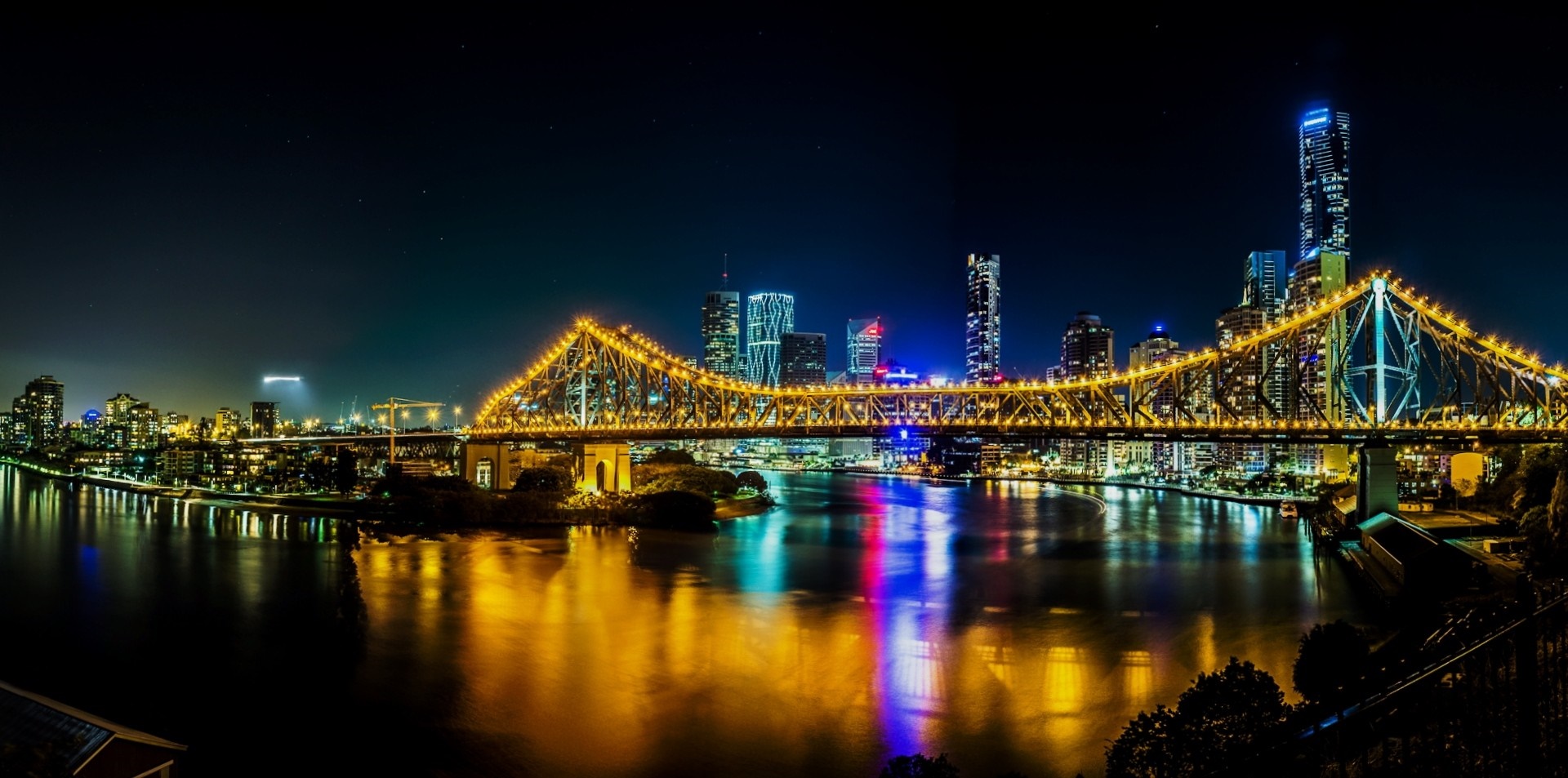 Cityscape with illuminated bridge and river at night HD Wallpaper