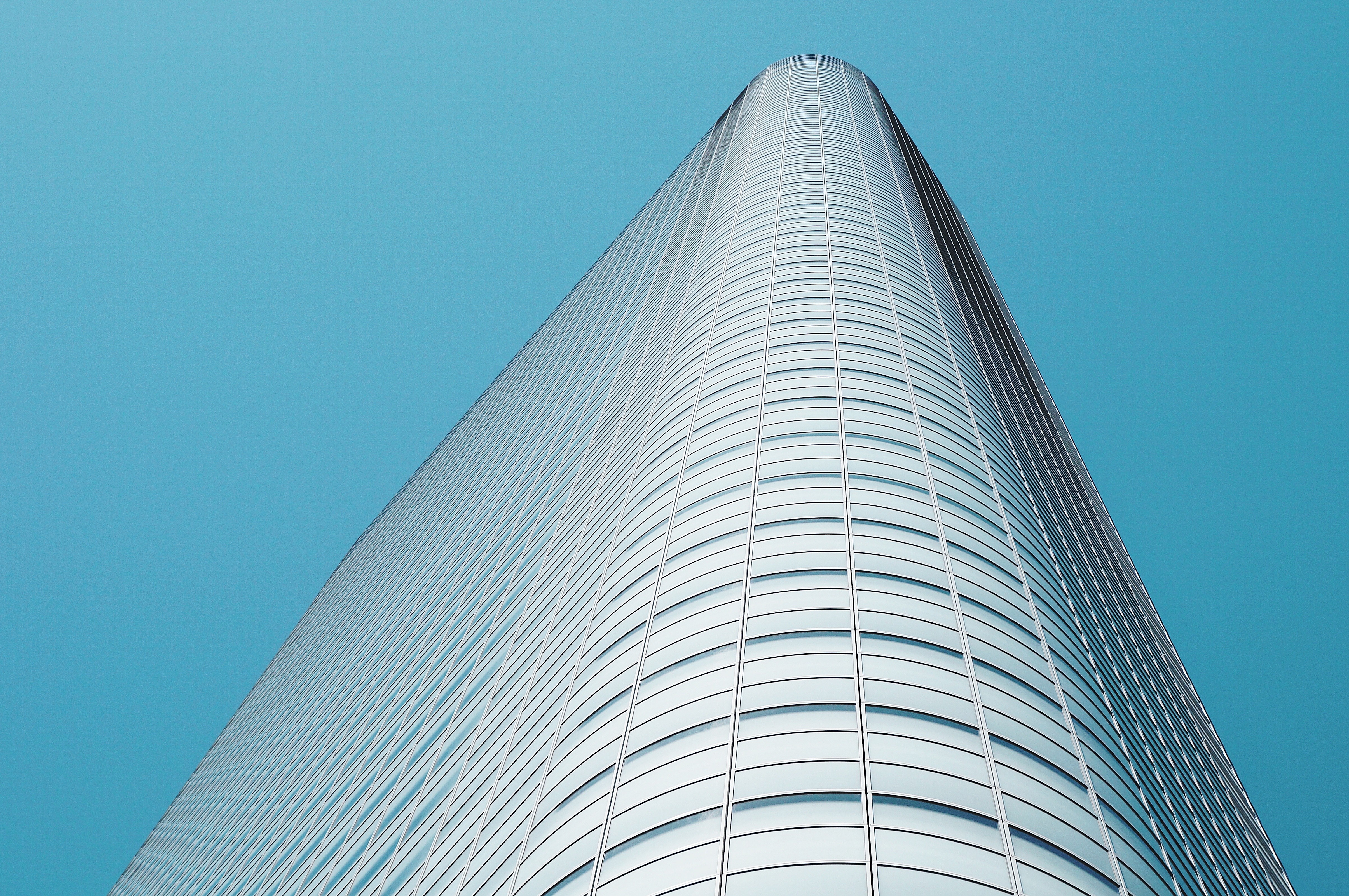 Modern glass skyscraper against a clear blue sky HD Wallpaper