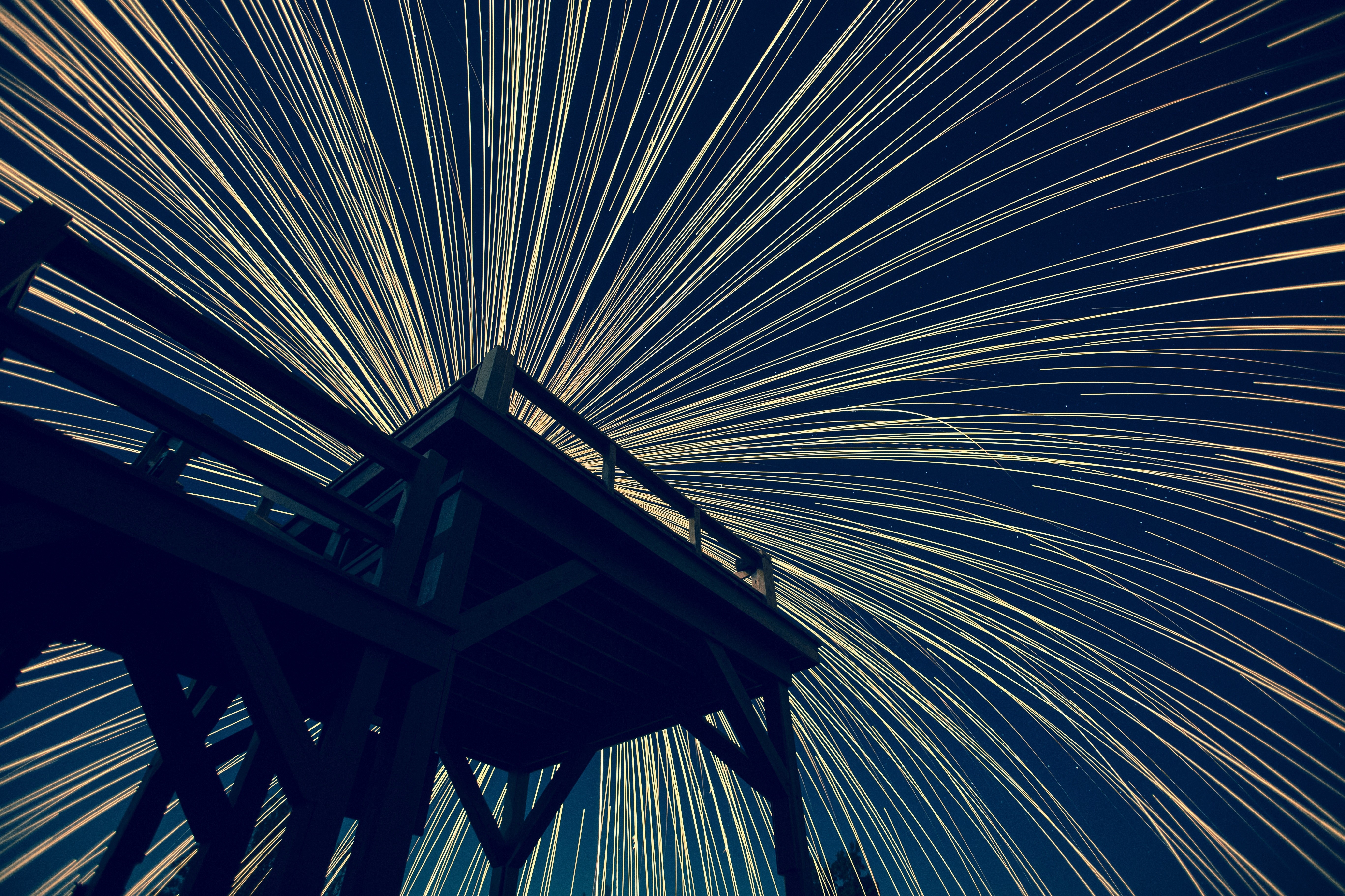Light trails from a wooden structure at night HD Wallpaper