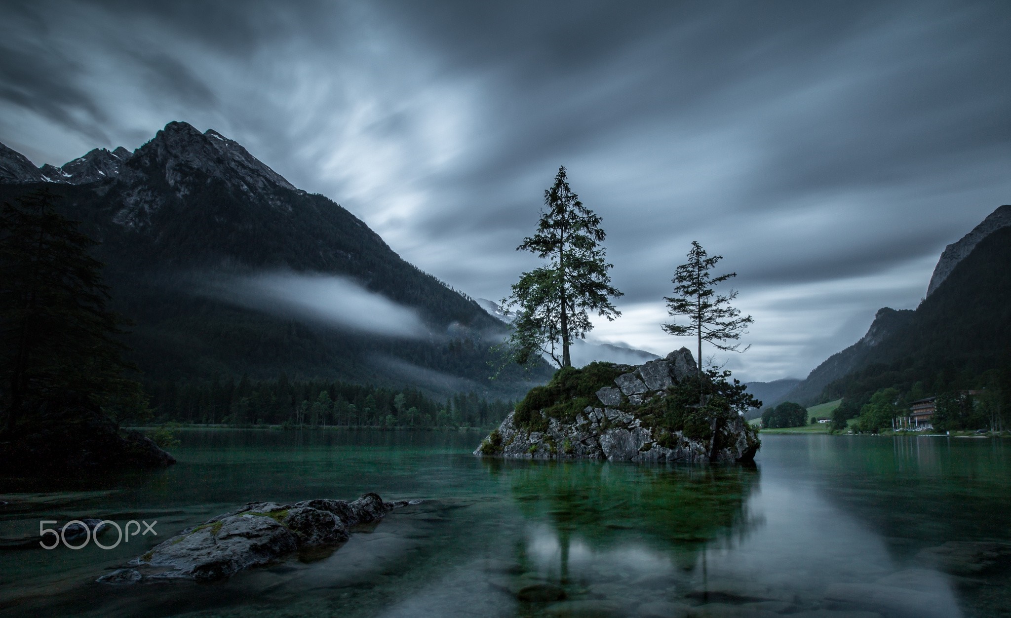Misty mountains reflected in a lake with island trees HD Wallpaper