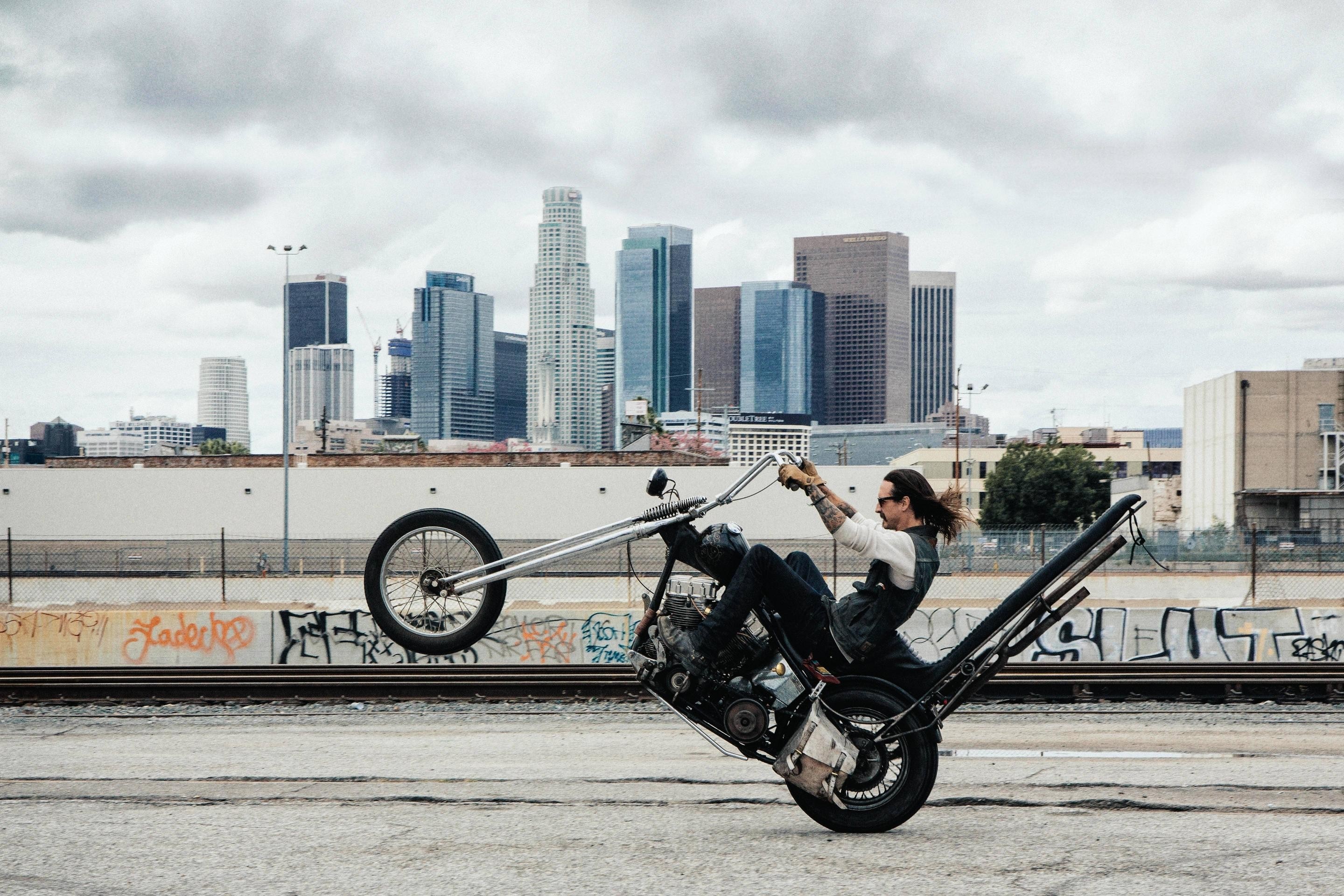 Man performing a wheelie on a custom chopper motorcycle in Los Angeles HD Wallpaper