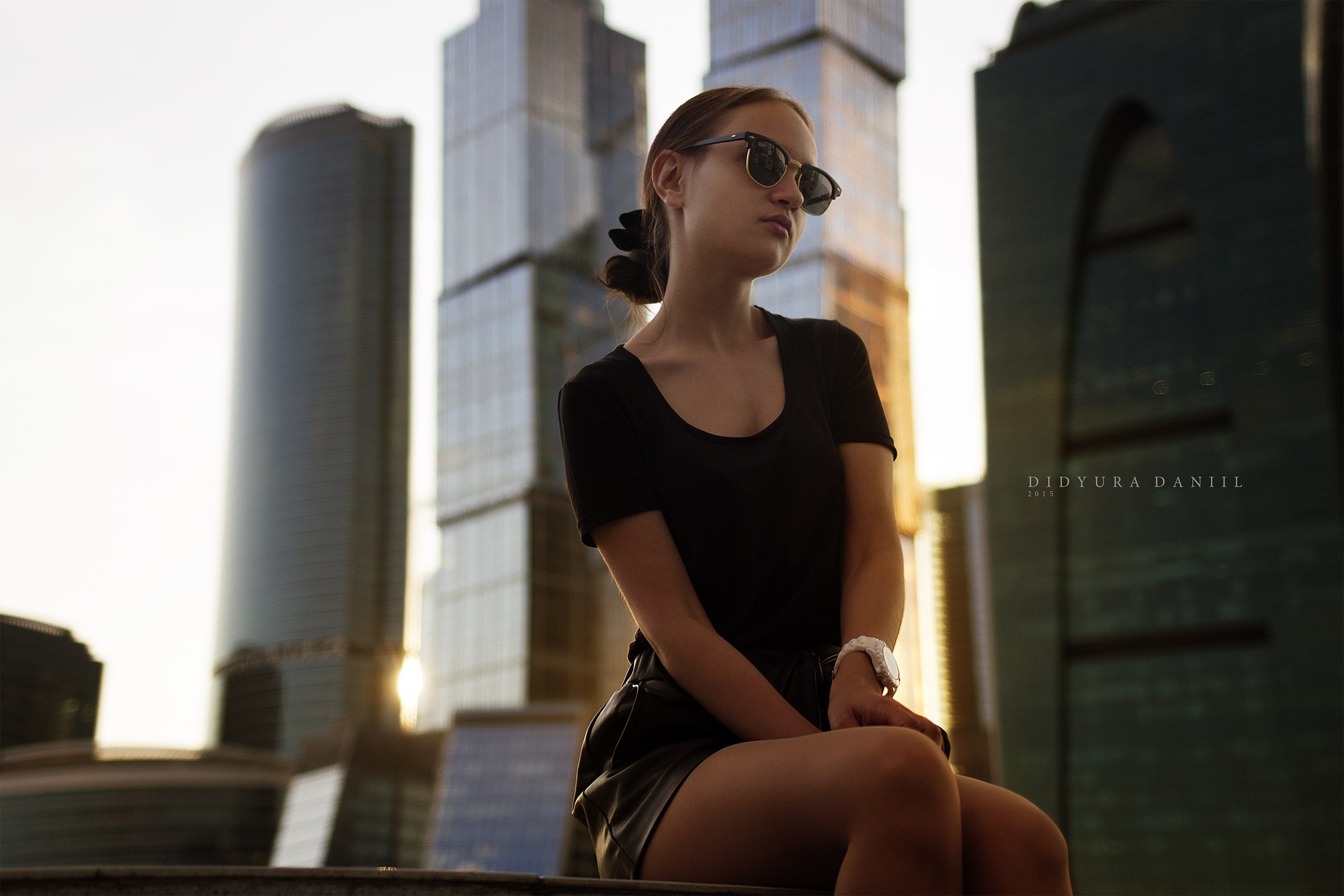 Woman in sunglasses sitting in a cityscape HD Wallpaper