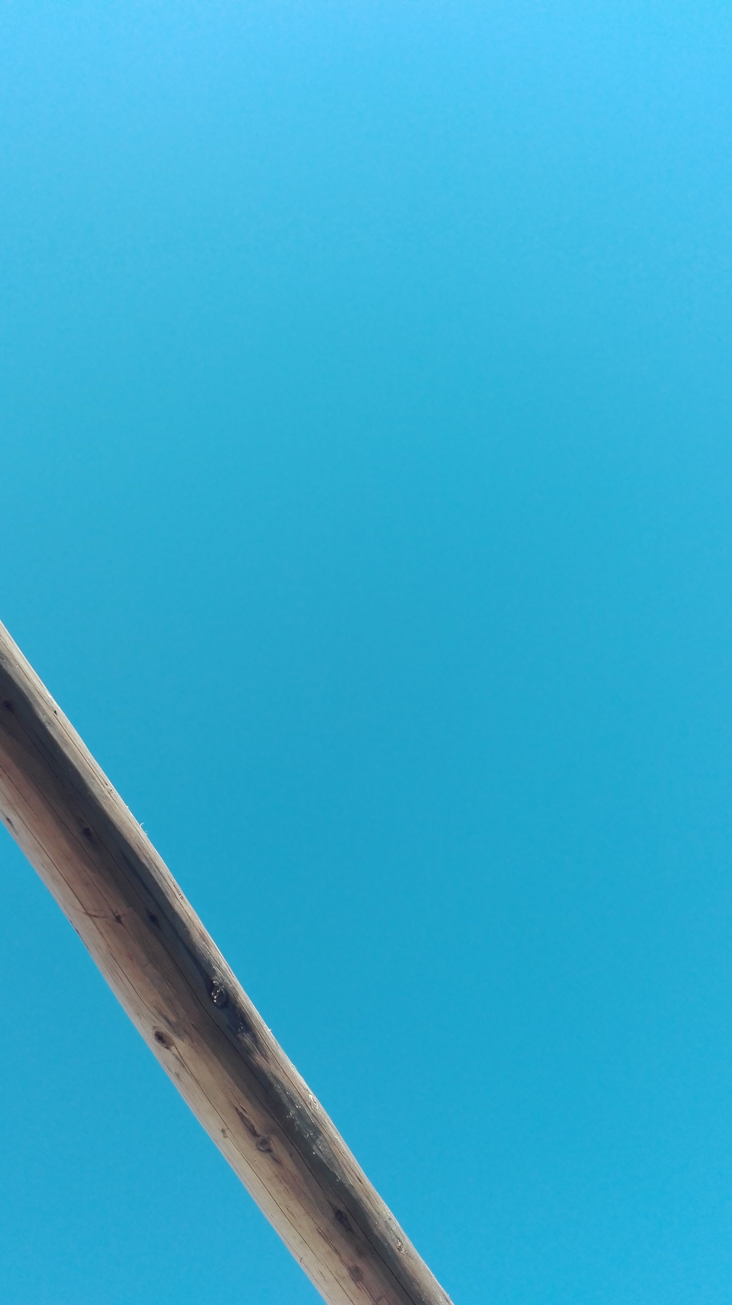 Wooden pole against a clear blue sky HD Wallpaper