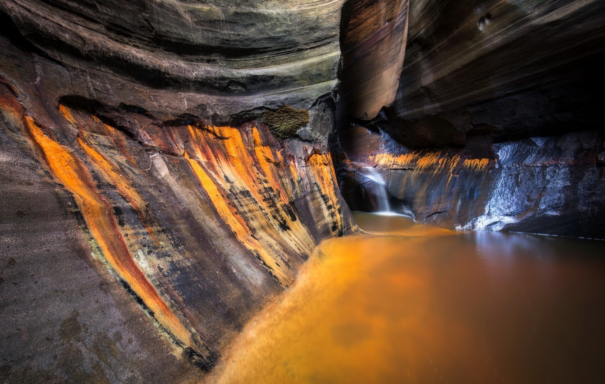 Cave with colorful mineral deposits and waterfall HD Wallpaper