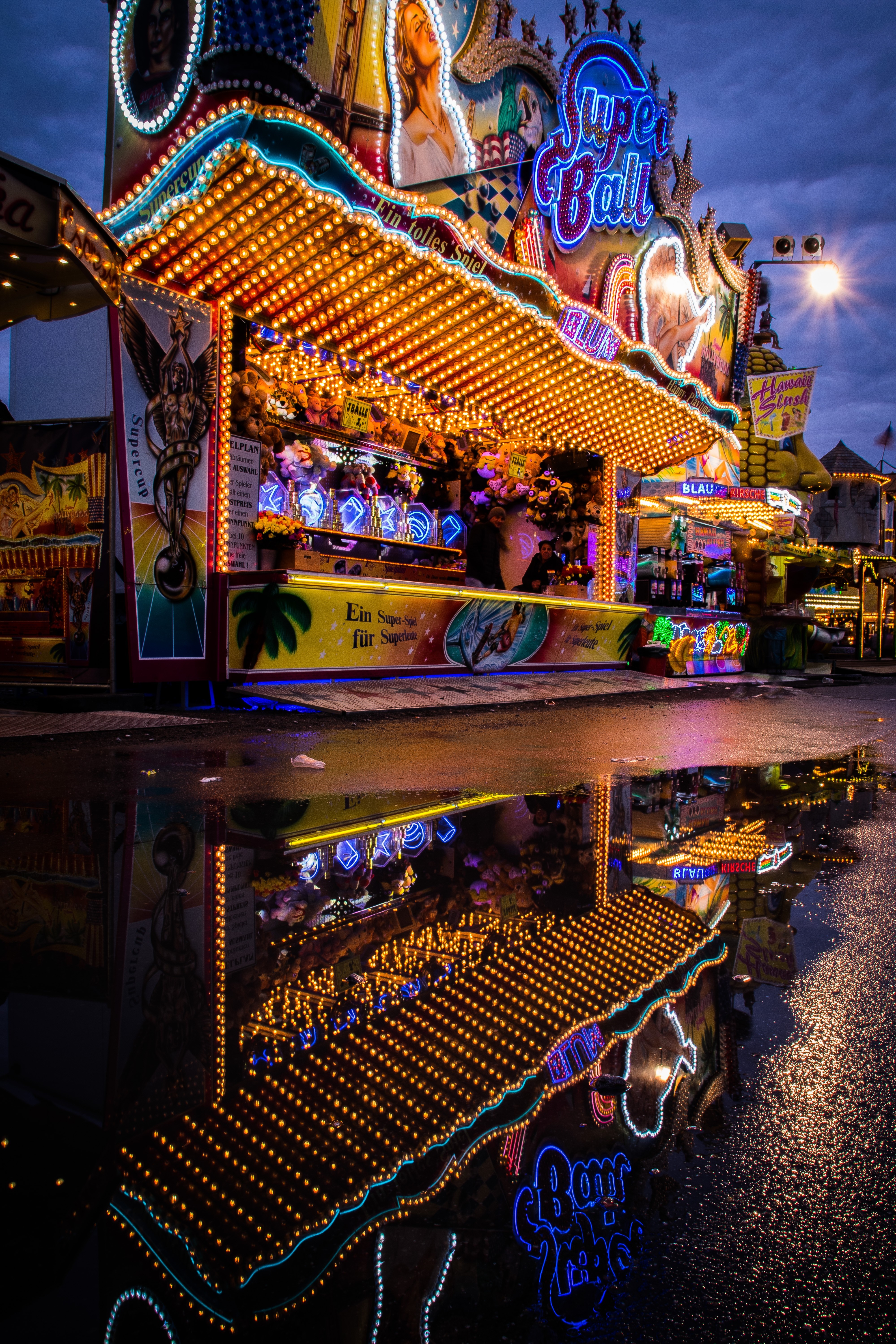 Amusement park stall with lights reflected in water HD Wallpaper