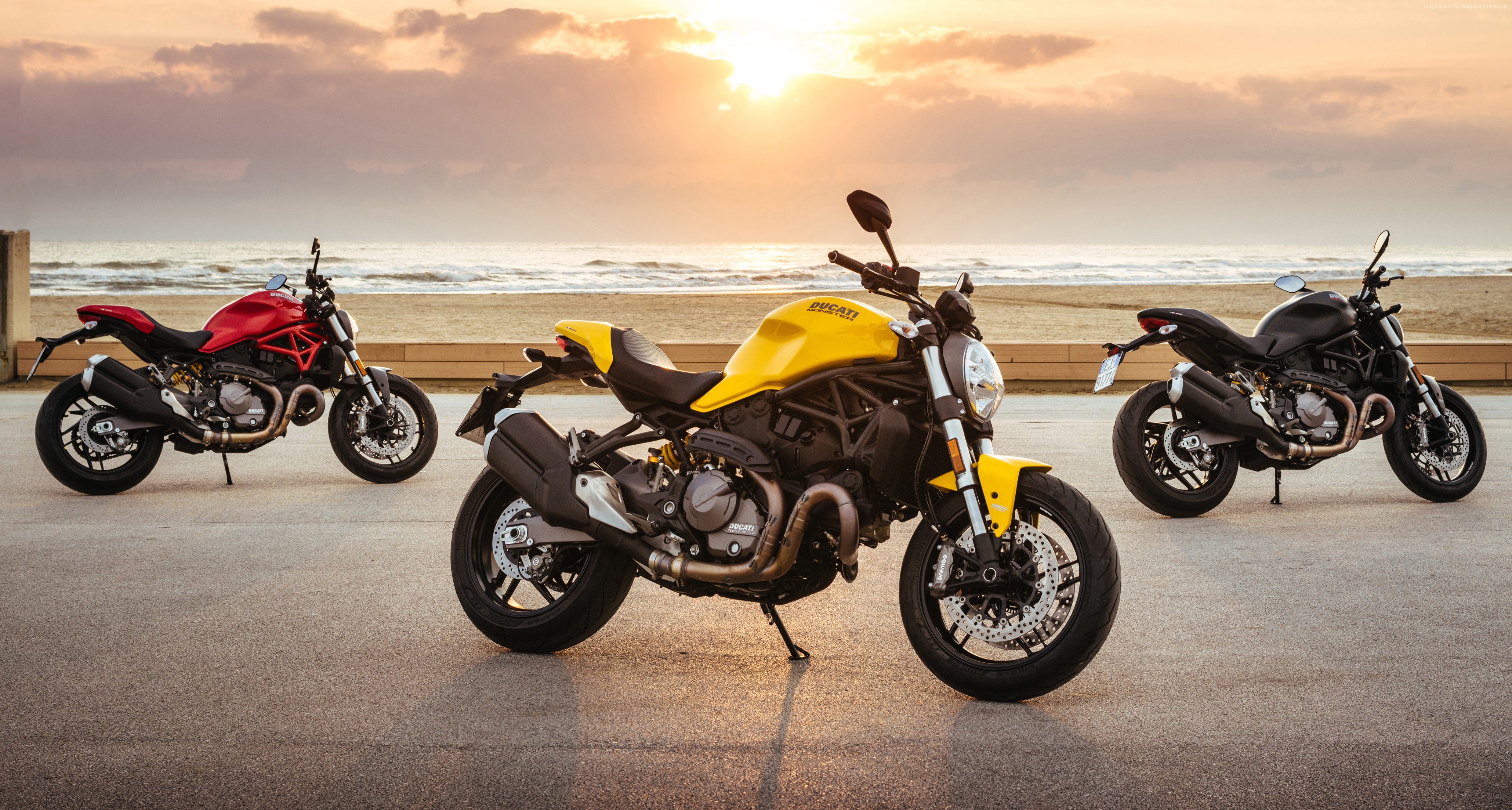 Three Ducati Monster 821 motorcycles on a beach at sunset HD Wallpaper
