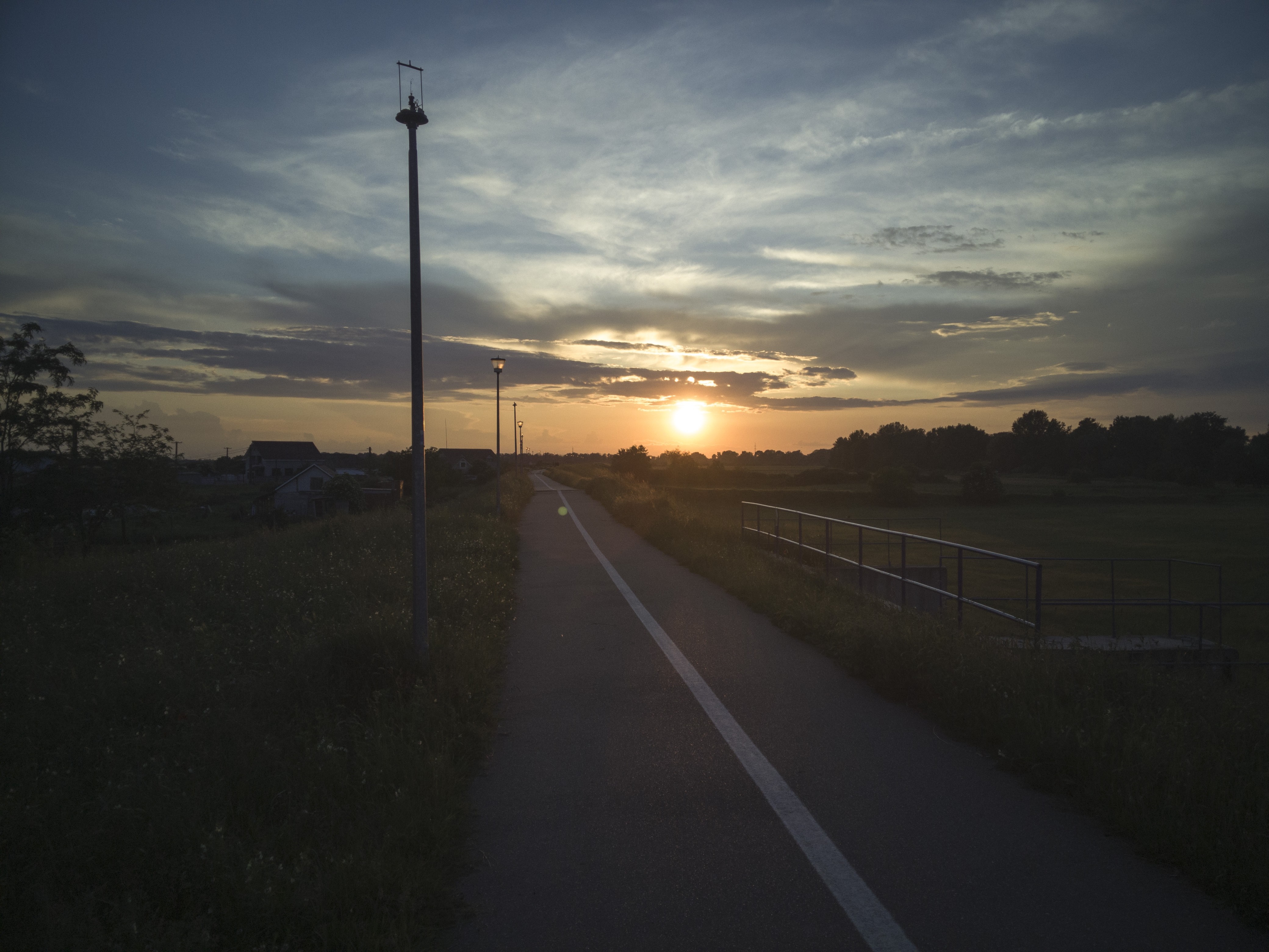 Road at sunset with clouds and streetlights HD Wallpaper