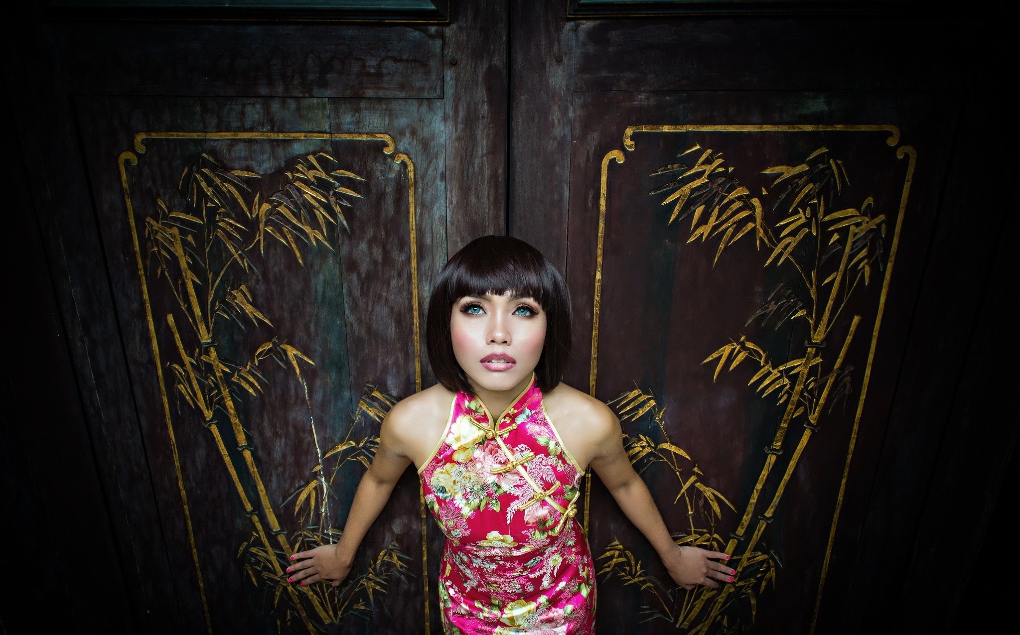 Woman in traditional Chinese dress in front of ornate doors HD Wallpaper