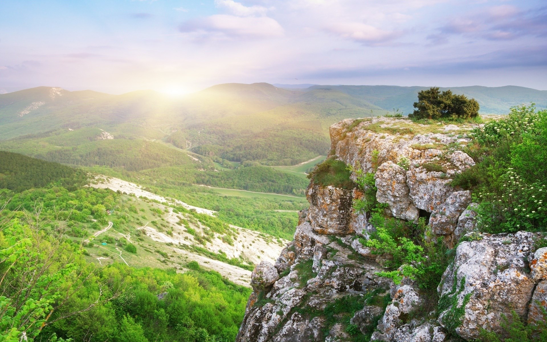 Rocky cliff overlooking a green valley at sunrise HD Wallpaper