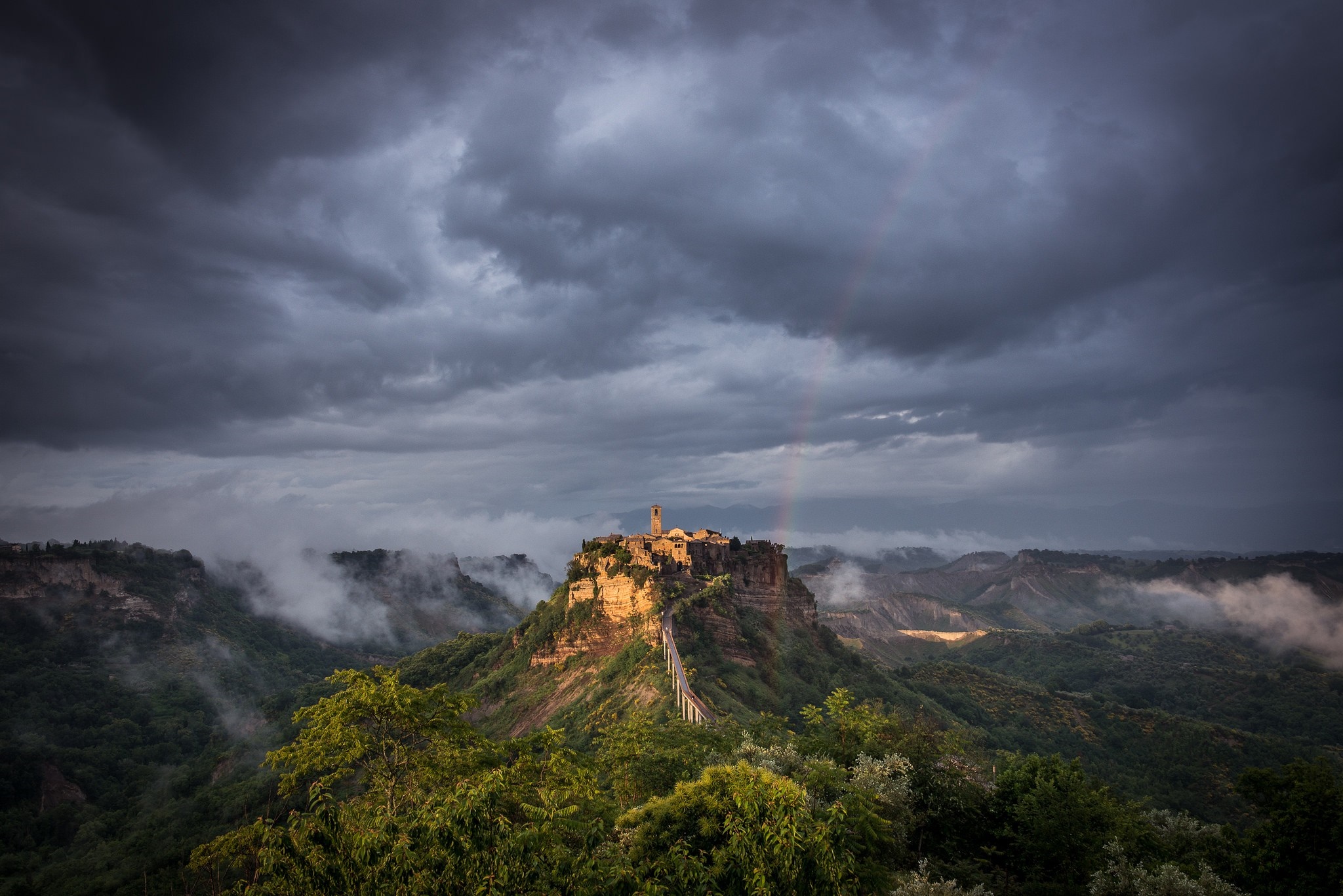 Civita di Bagnoregio, Italy, under stormy skies with a rainbow HD Wallpaper