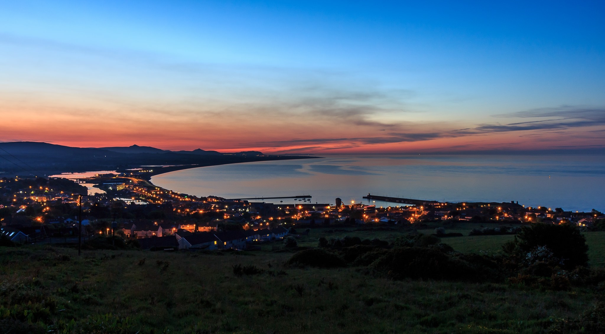 Coastal town at dusk with mountains and sea HD Wallpaper