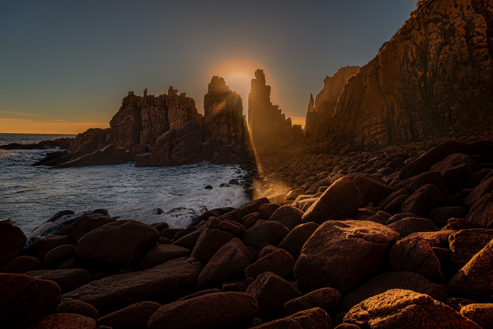 Rocky coast with sunbeams at sunset HD Wallpaper