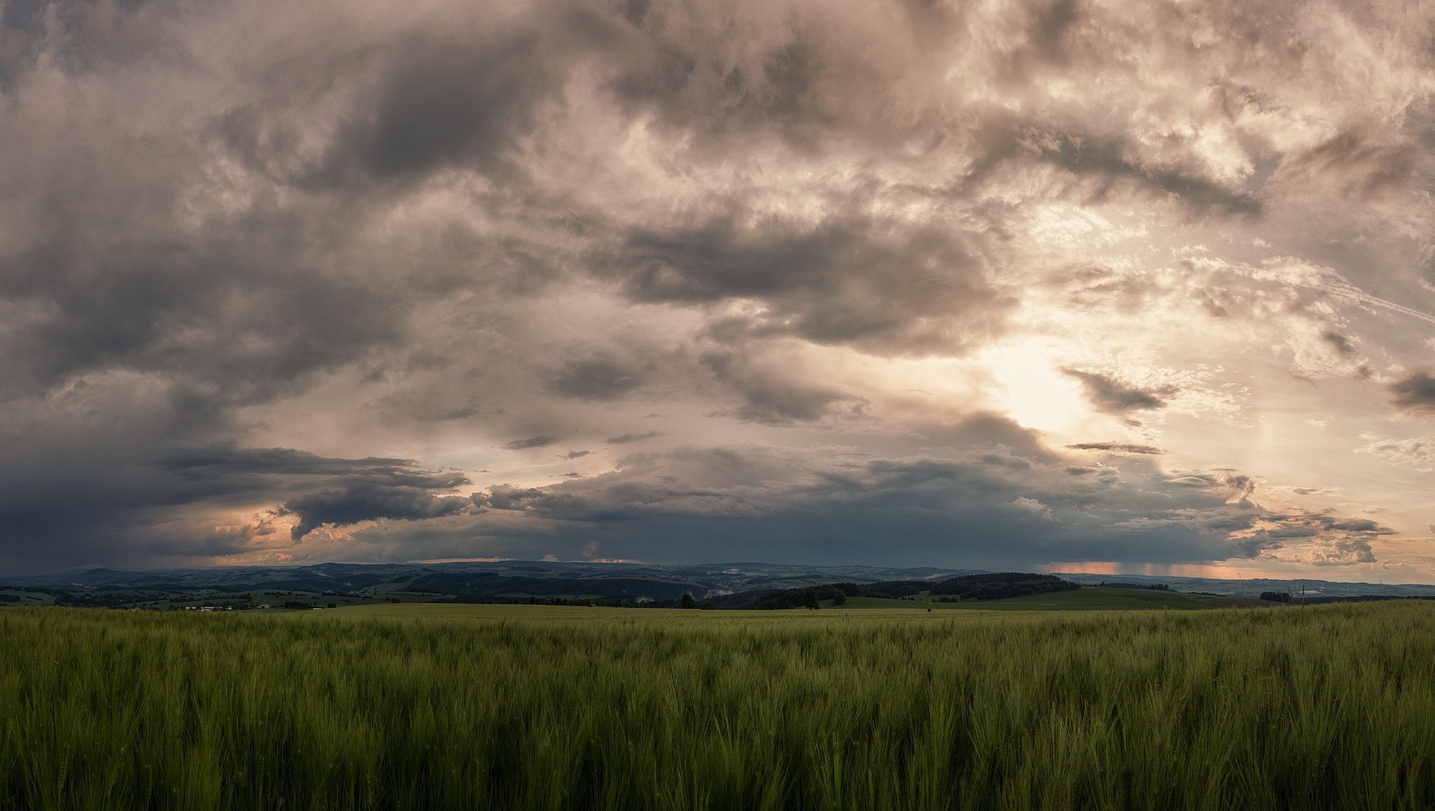 Stormy clouds over a green field at sunset HD Wallpaper
