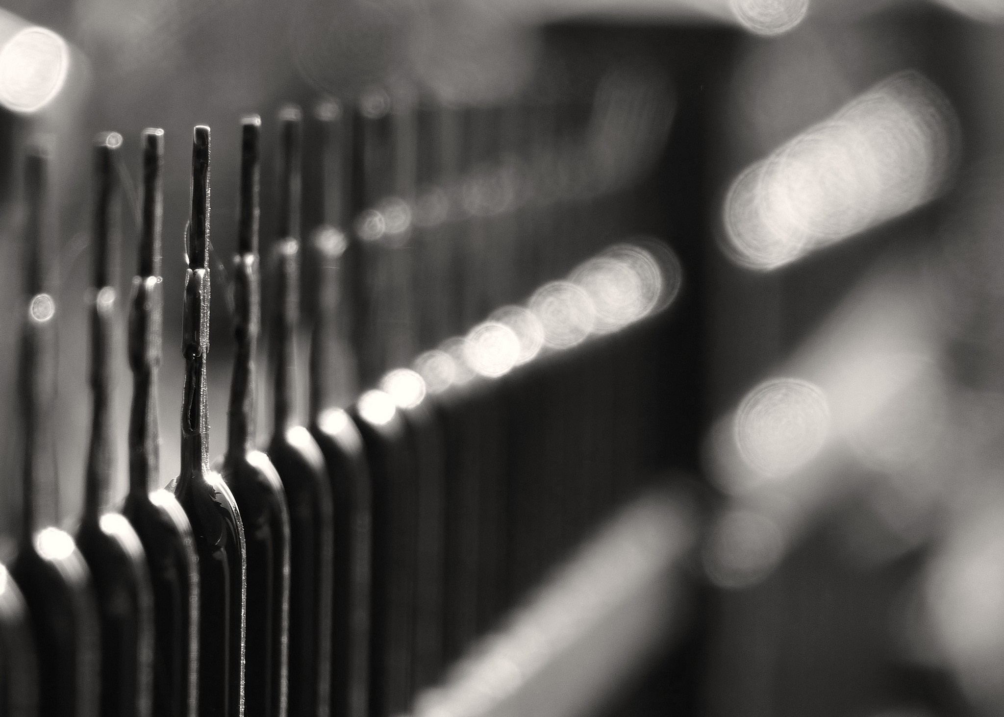 Monochrome close-up of a row of metal objects with bokeh lights HD Wallpaper