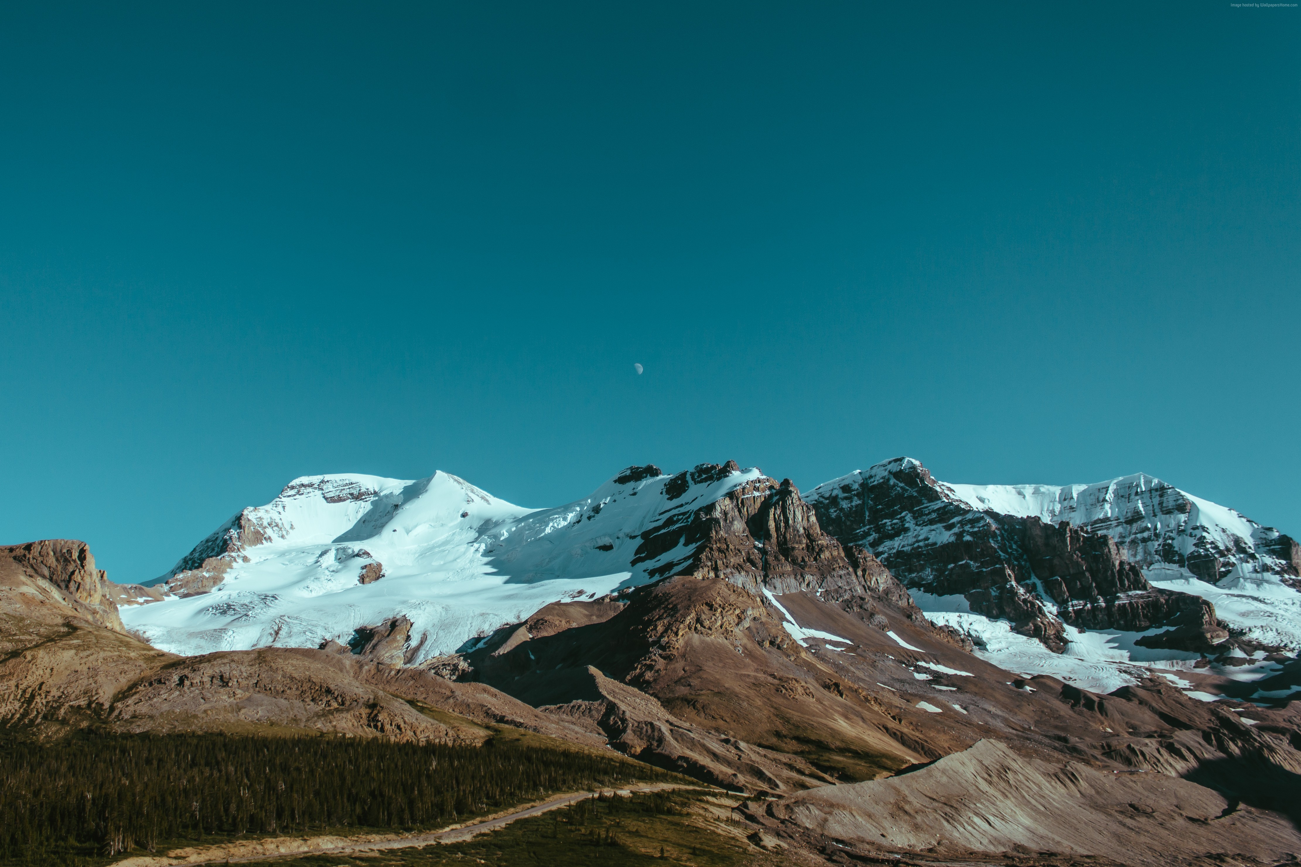 Snow-capped mountains under a clear blue sky with a crescent moon HD Wallpaper