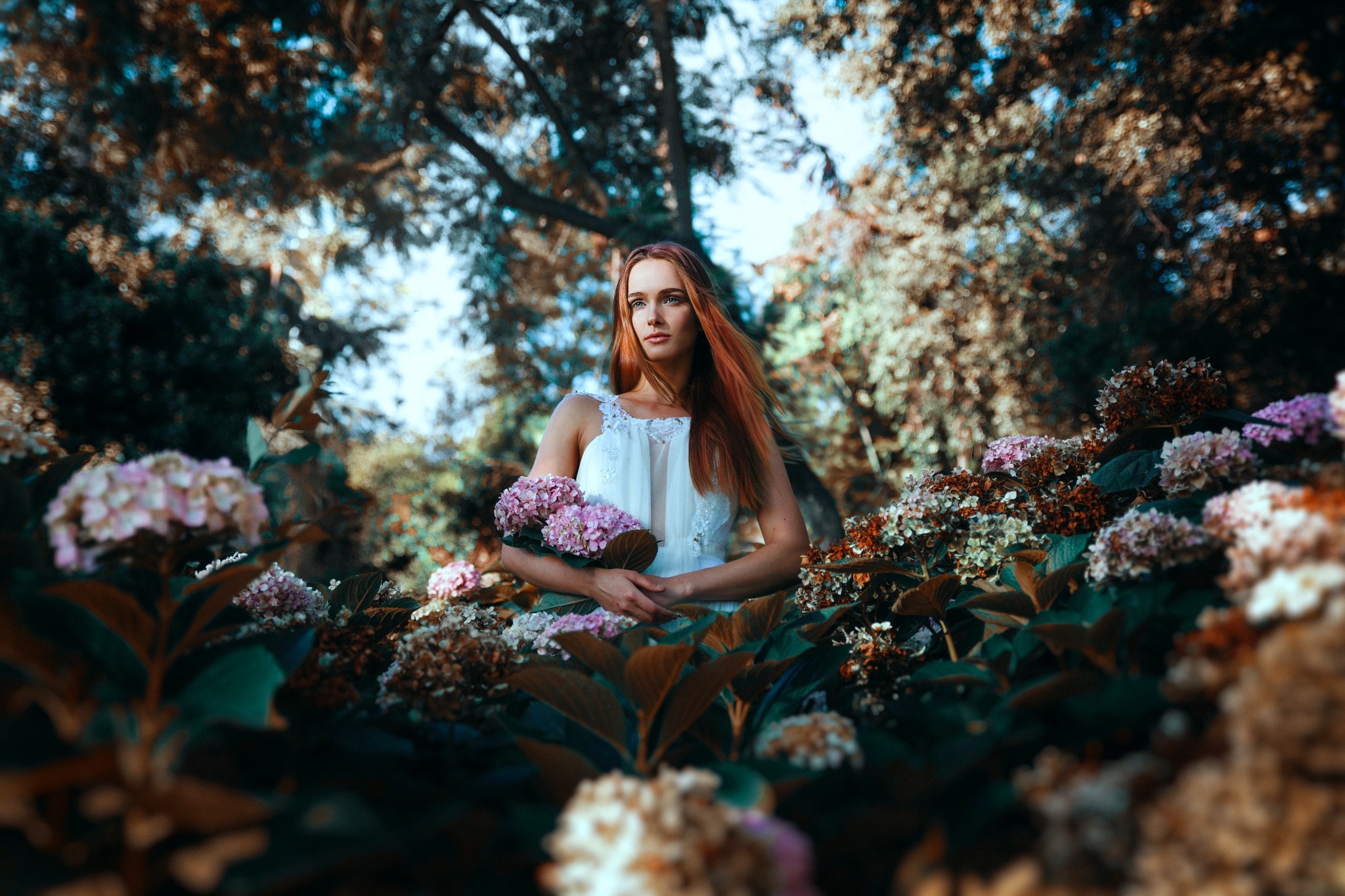 Woman in white dress holding flowers in a garden HD Wallpaper
