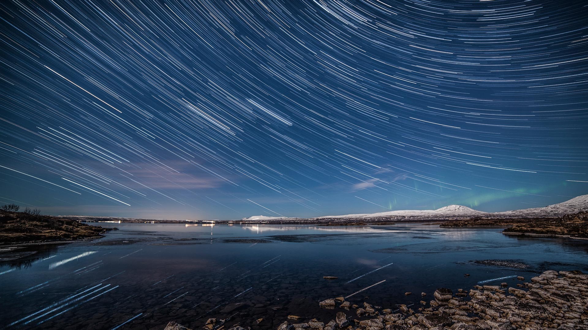 Star trails over a frozen lake with aurora borealis HD Wallpaper