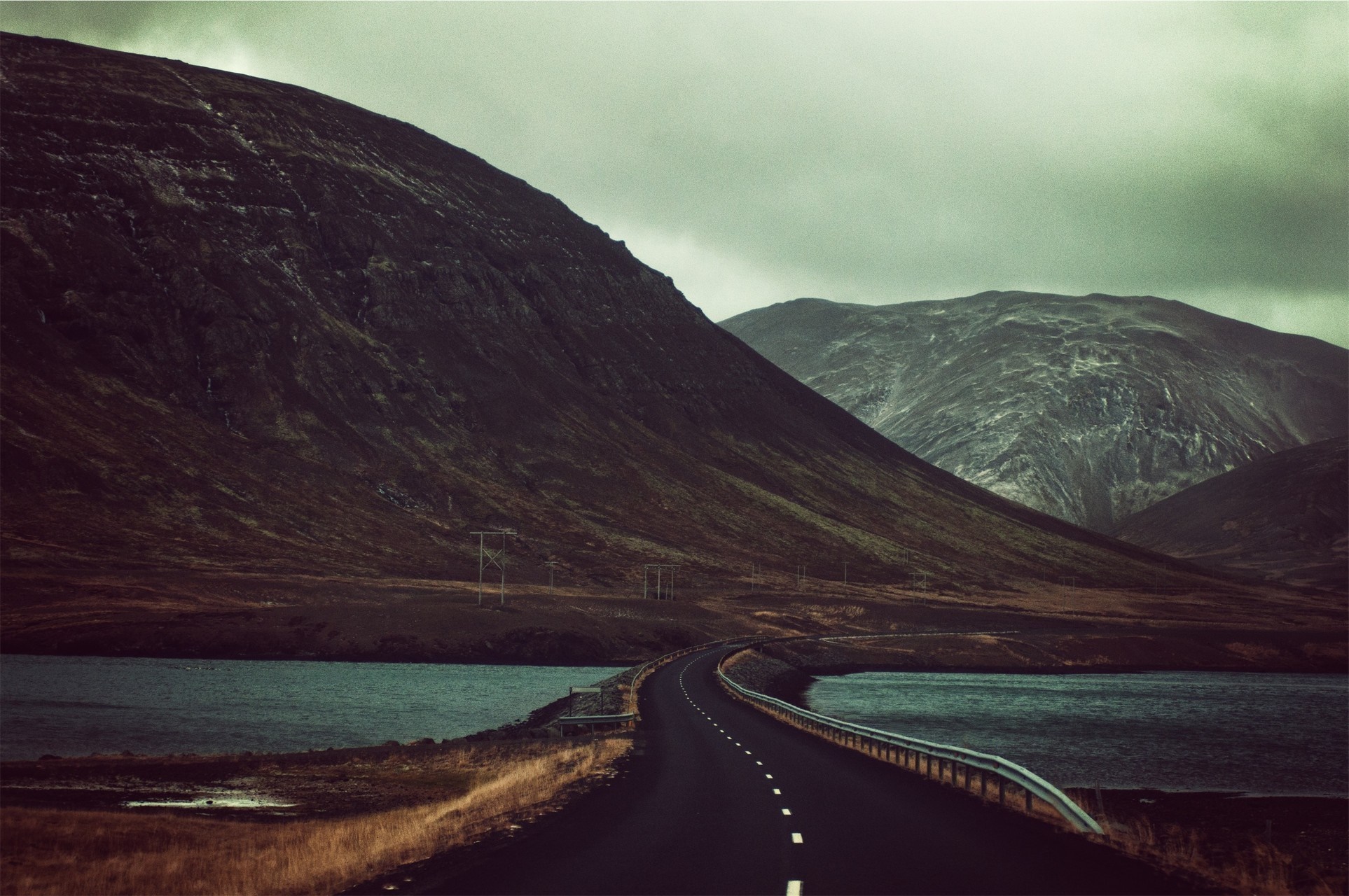 Road through mountains by a lake HD Wallpaper