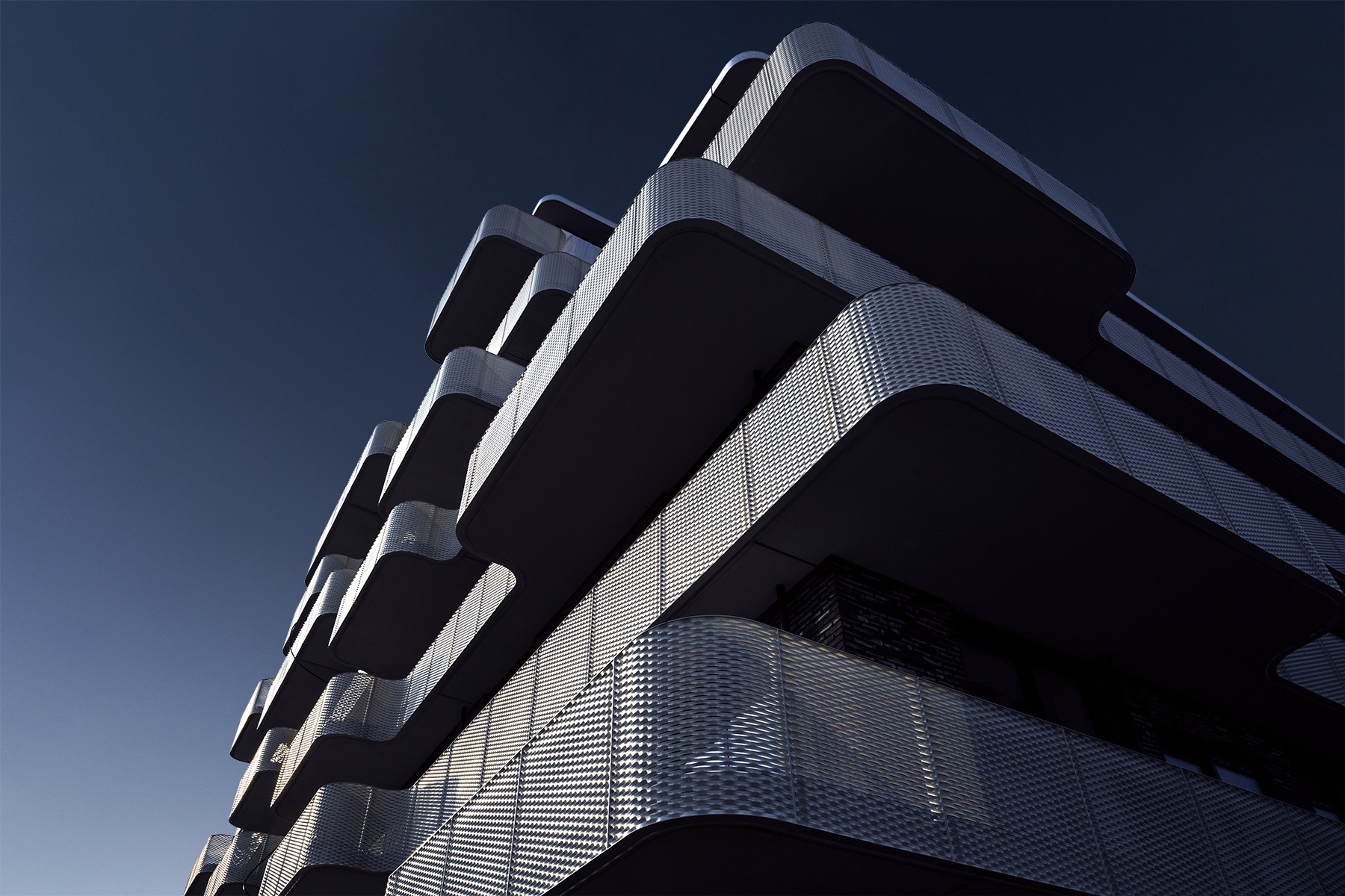 Modern building with balconies against a dark blue sky HD Wallpaper