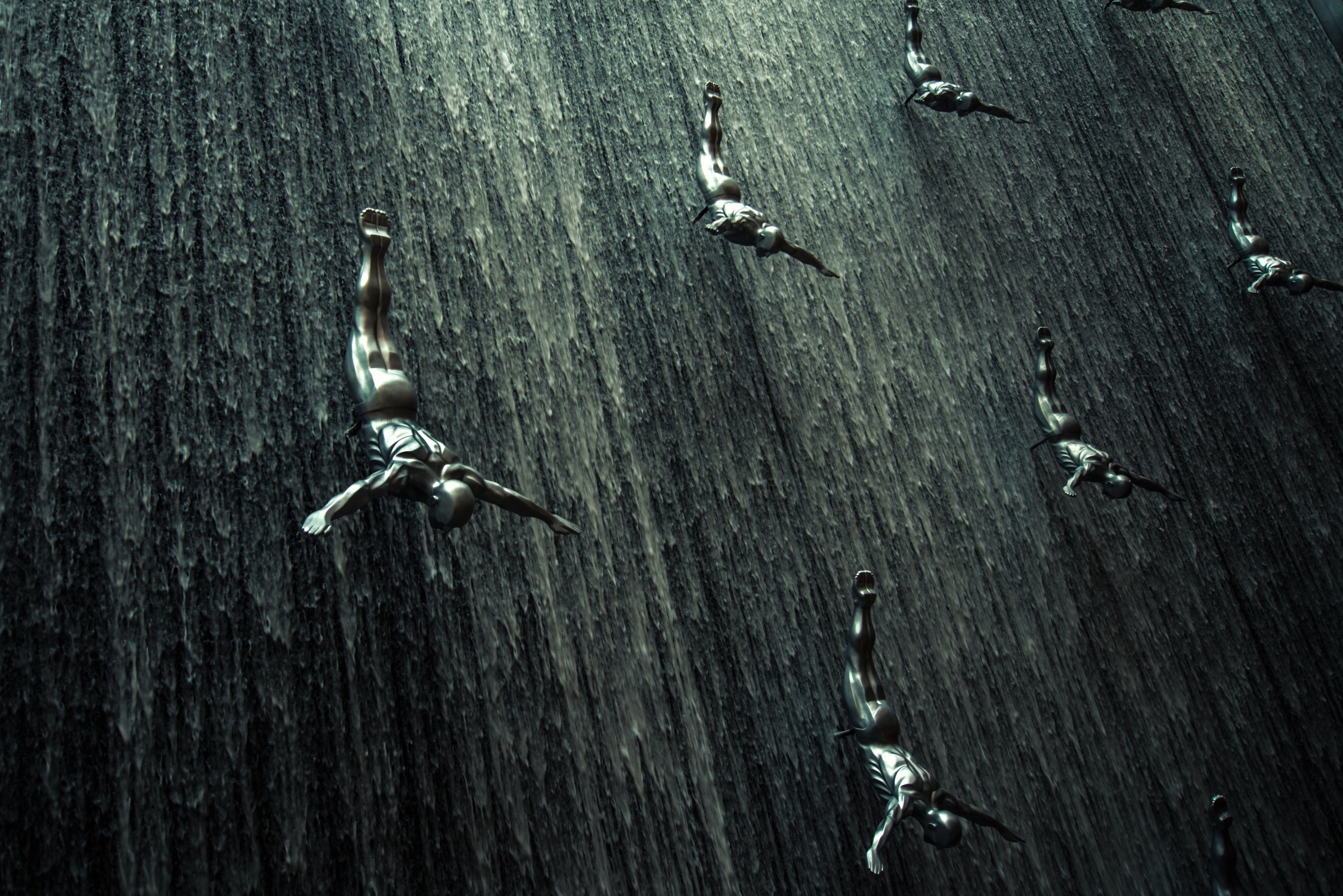 People diving down a dark waterfall HD Wallpaper