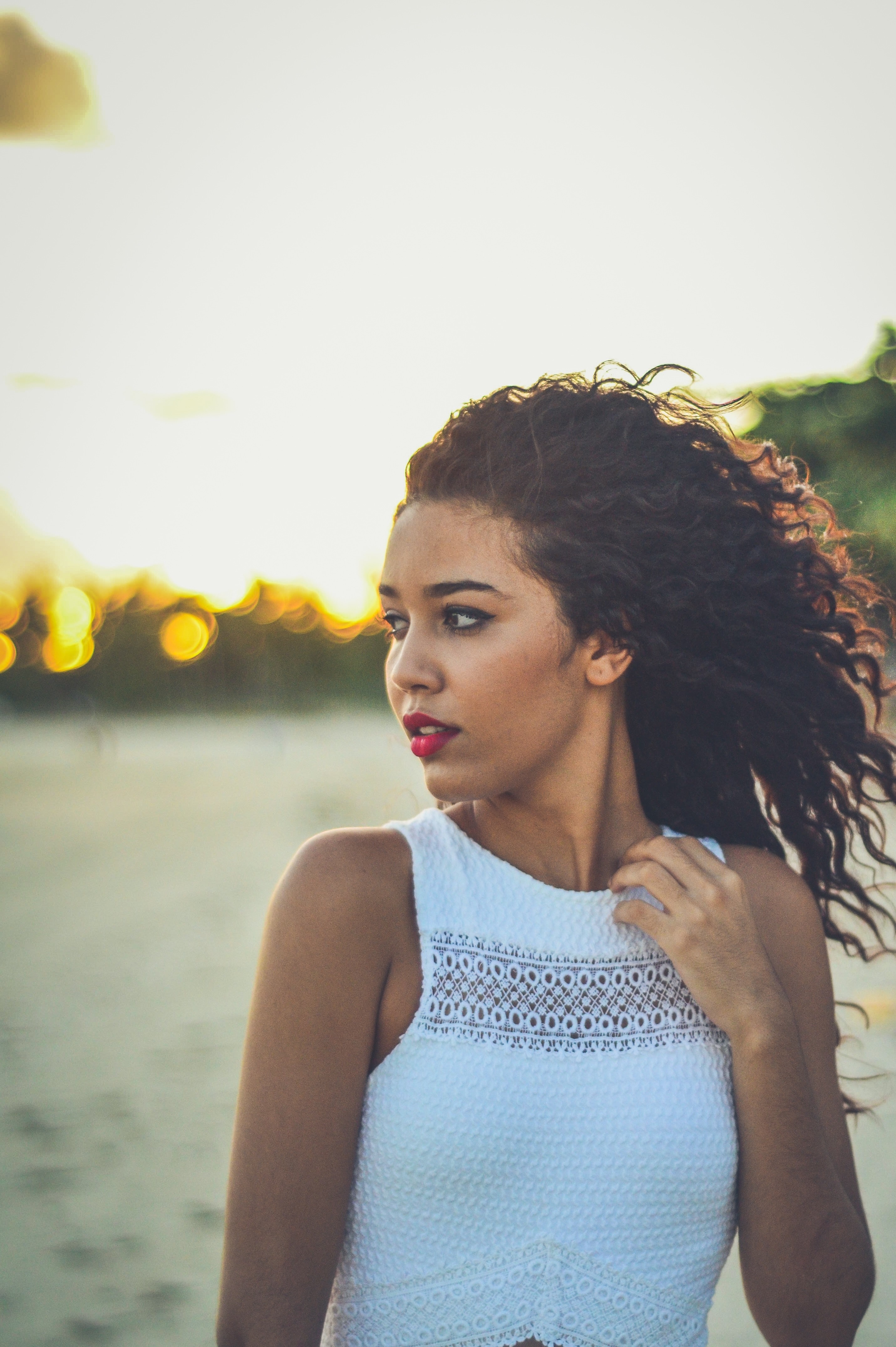 Woman with curly brown hair on a beach at sunset HD Wallpaper