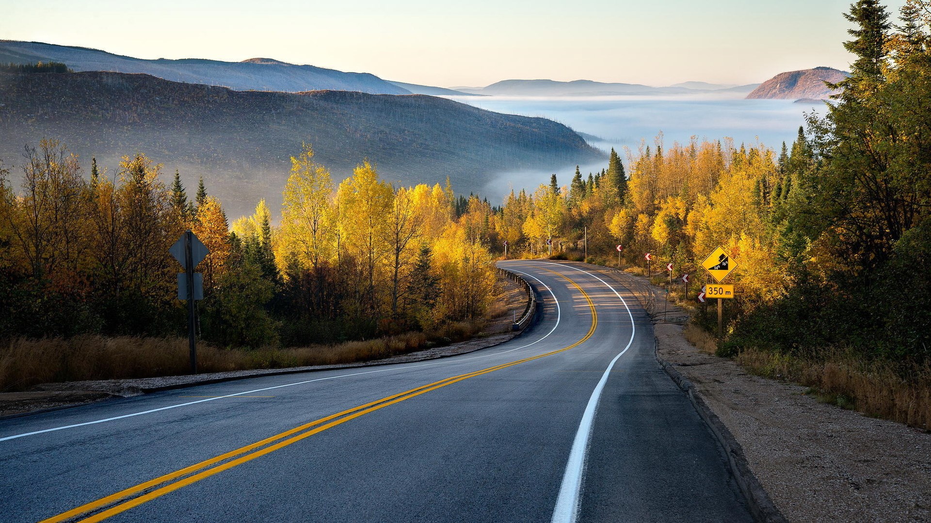Autumn road through misty mountains HD Wallpaper