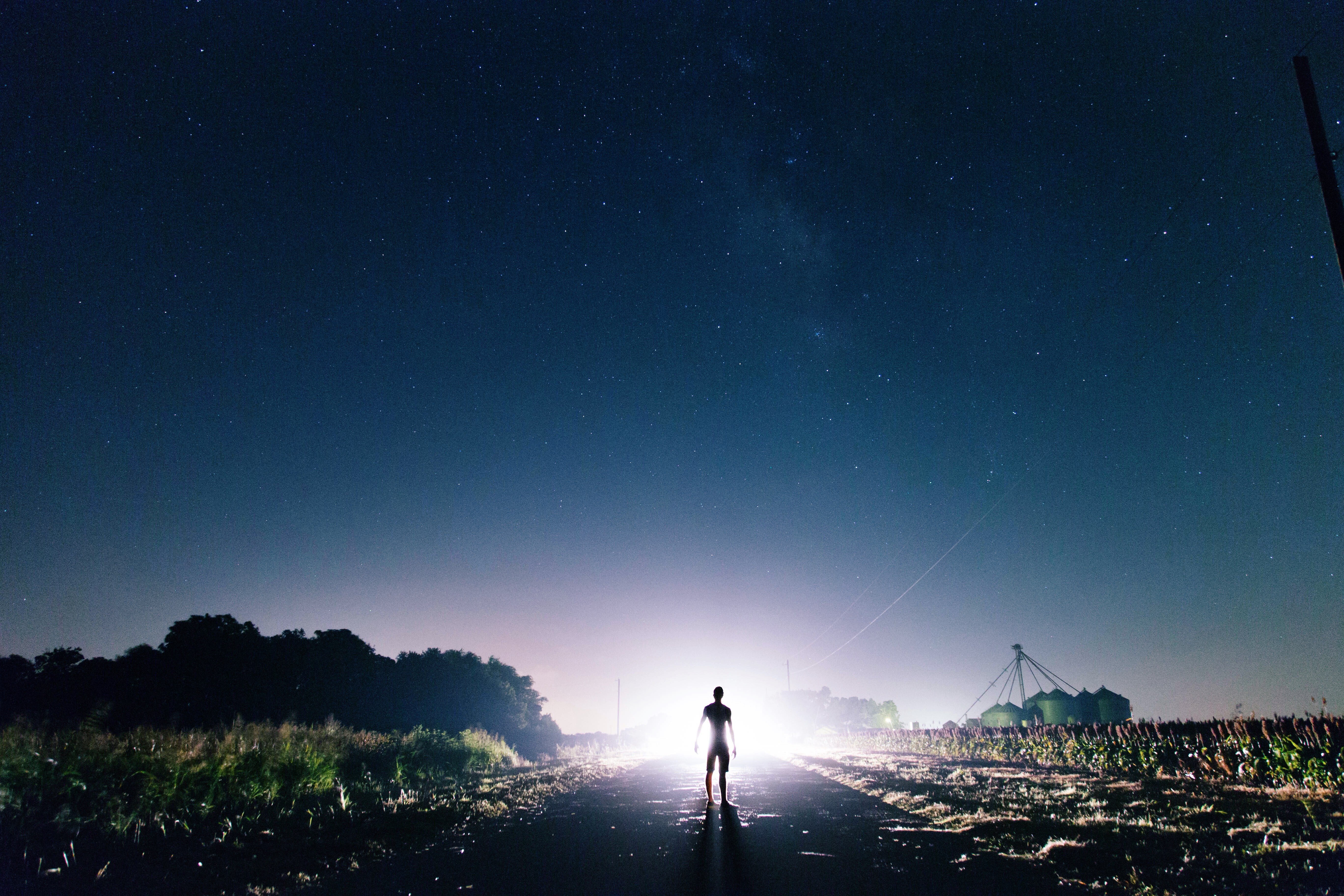 Person standing on a road at night under stars HD Wallpaper