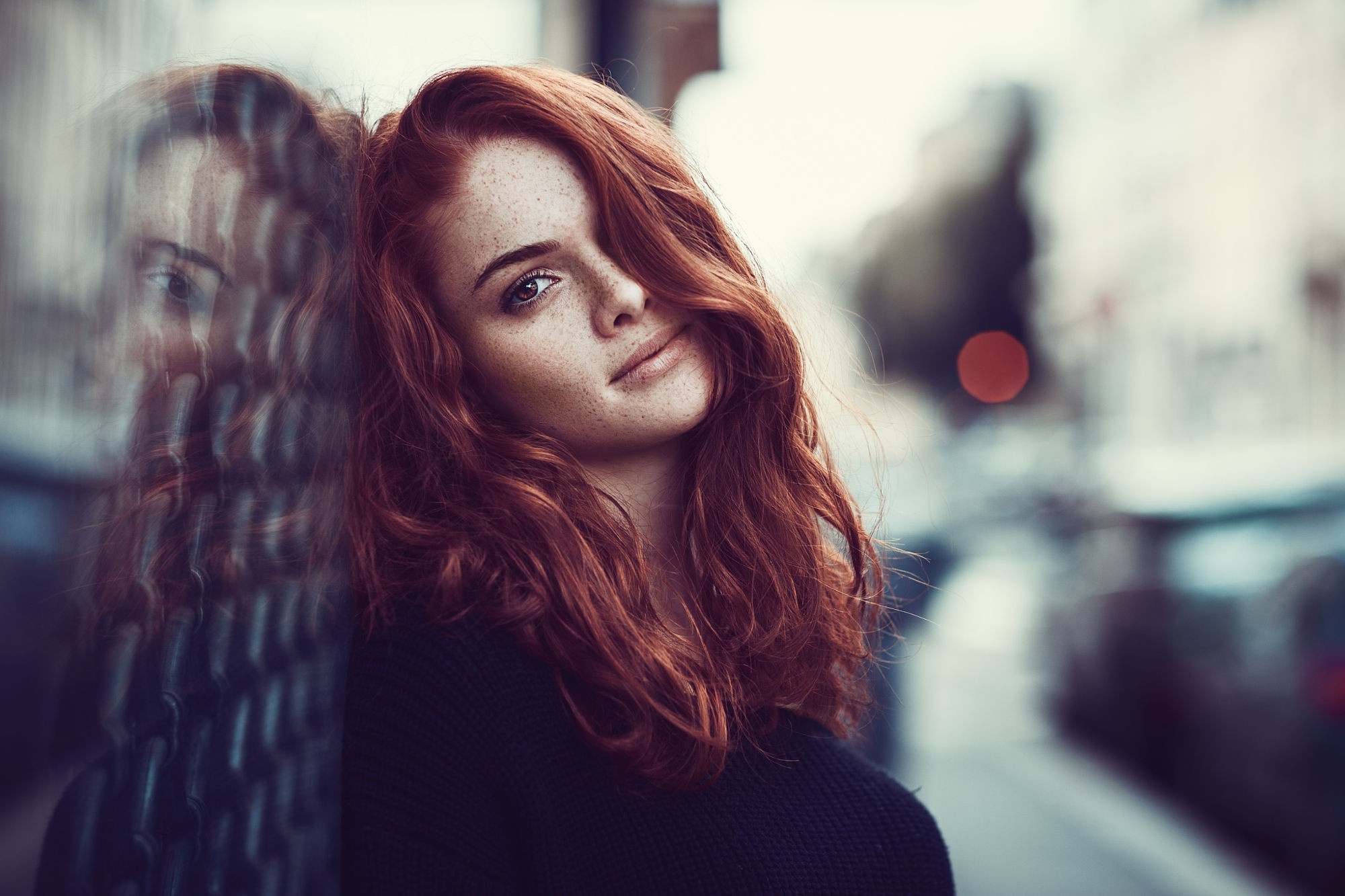 Redhead woman with freckles leaning against a glass surface HD Wallpaper
