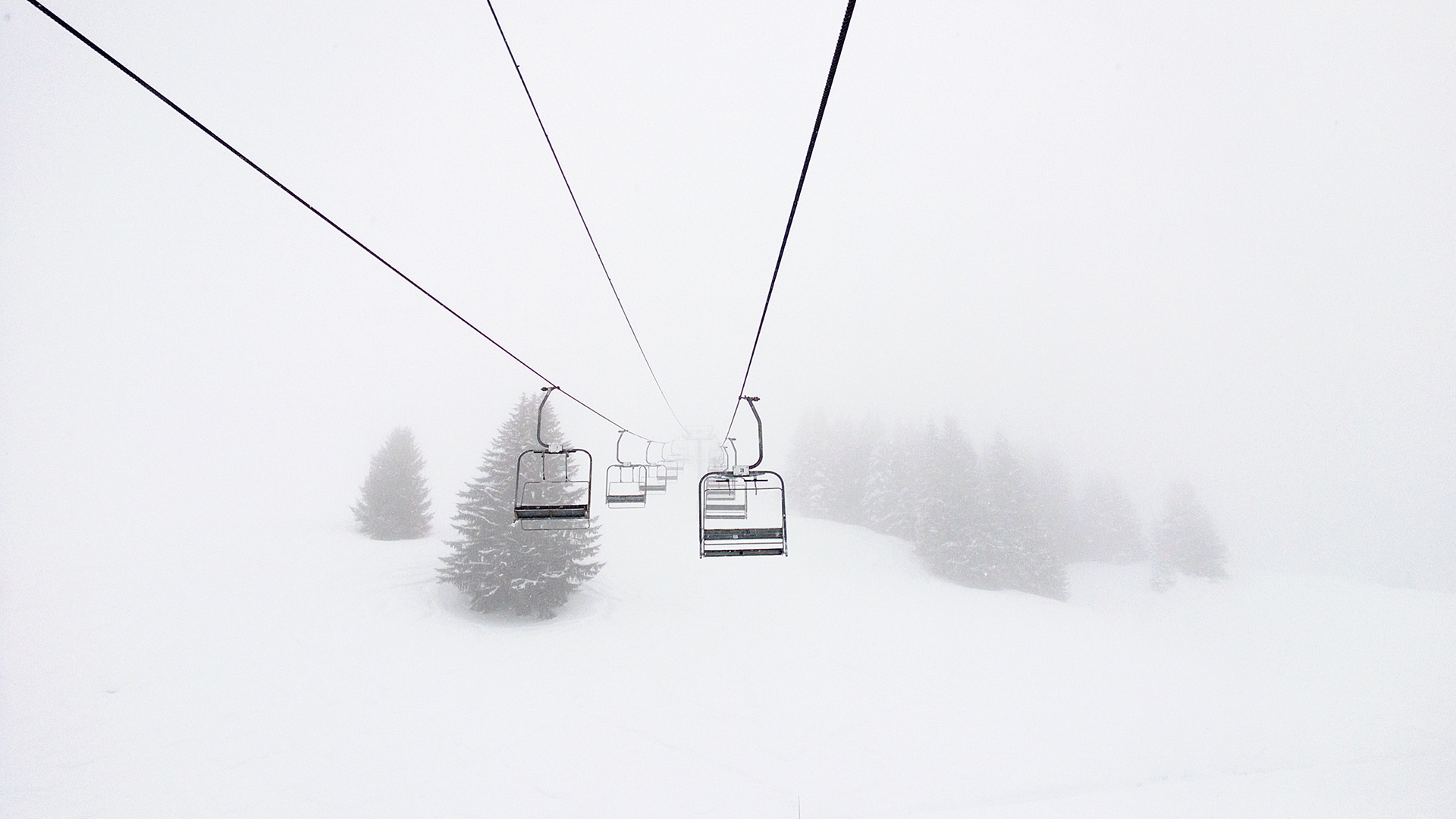 Ski lift in a snowy blizzard with pine trees HD Wallpaper