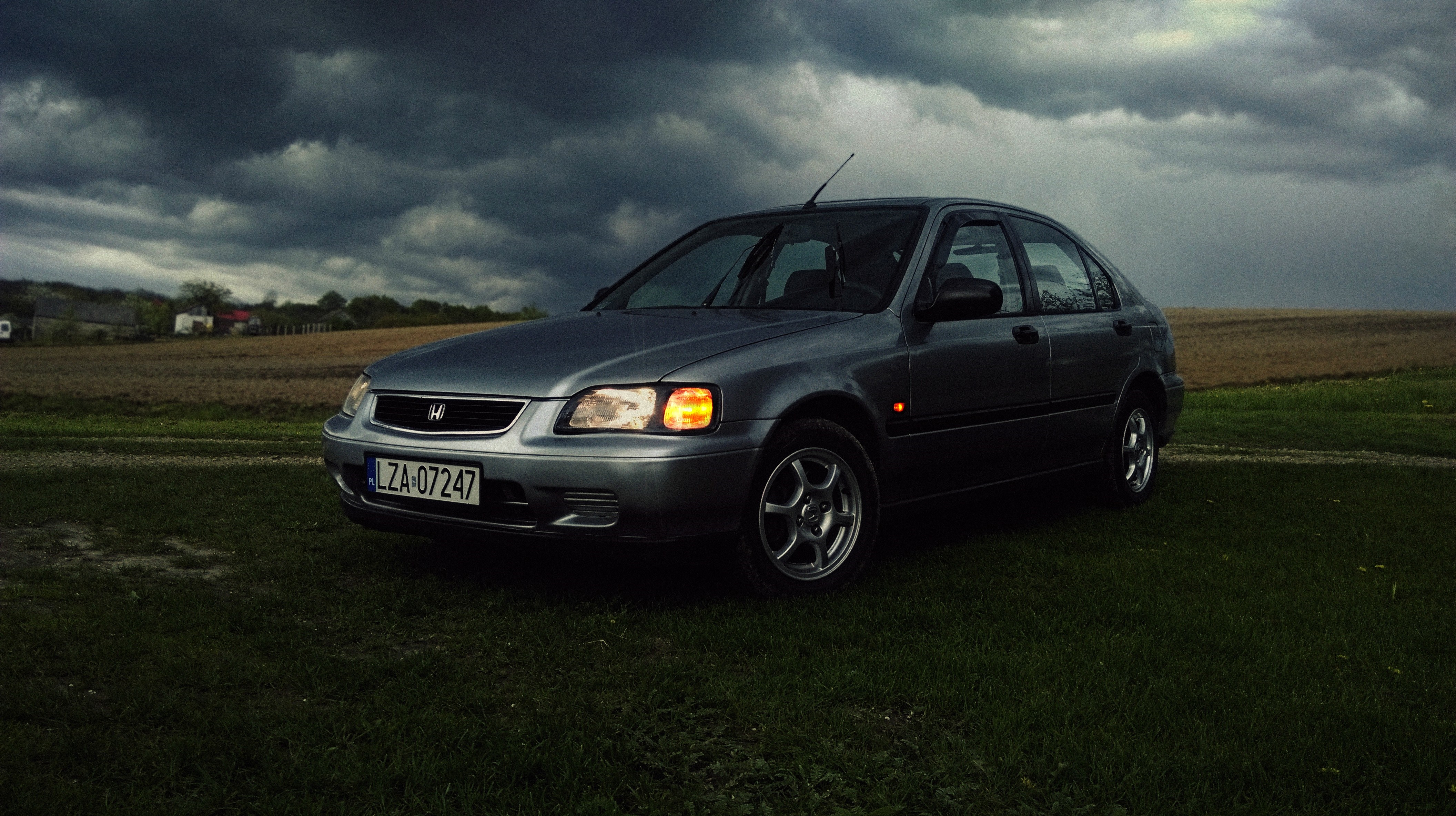 Honda Civic in a field under stormy clouds HD Wallpaper