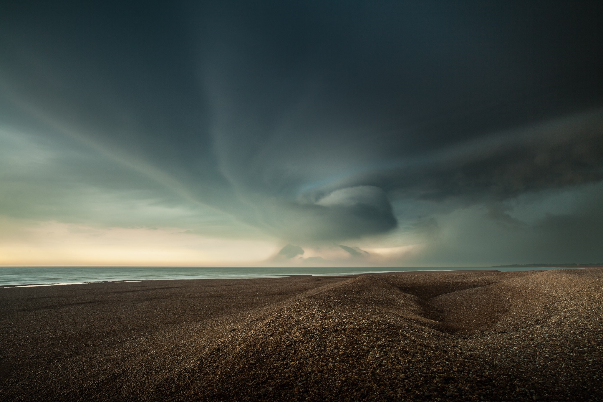 Storm clouds over a pebble beach and the sea HD Wallpaper