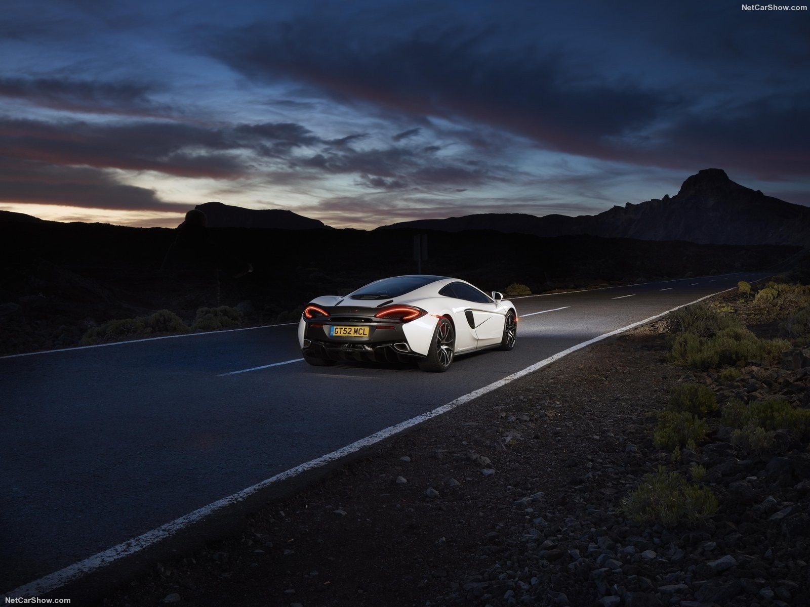 White McLaren 570GT driving on a road at dusk HD Wallpaper