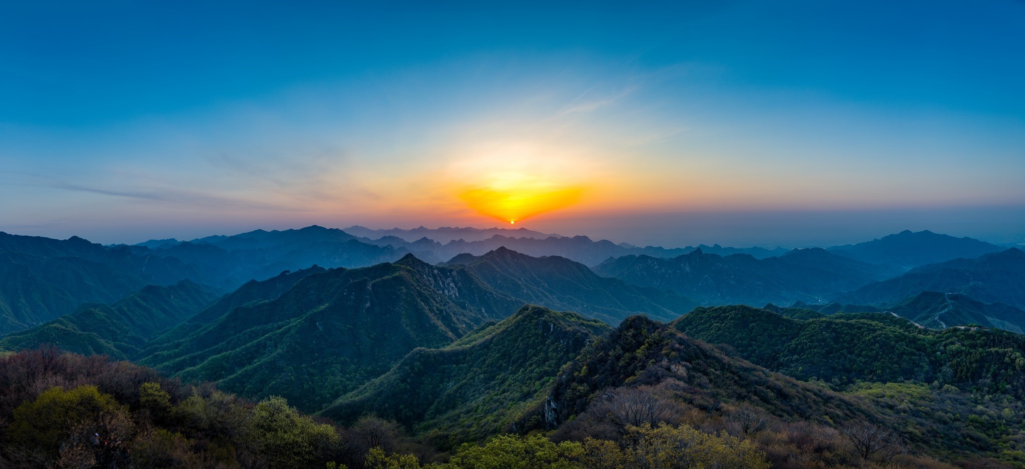 Panoramic mountain range at sunrise with sun setting behind peaks HD Wallpaper