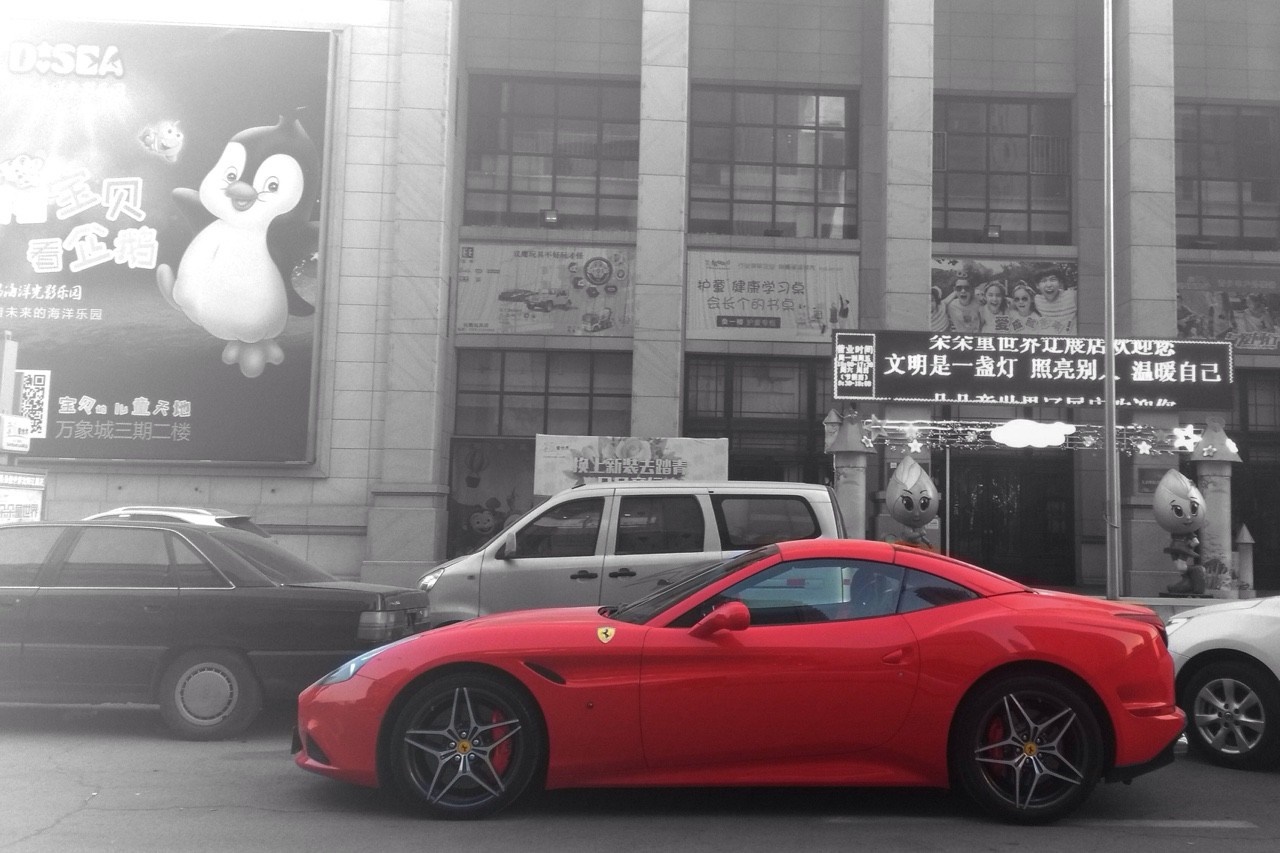 Red Ferrari California parked on a street with a building in the background HD Wallpaper