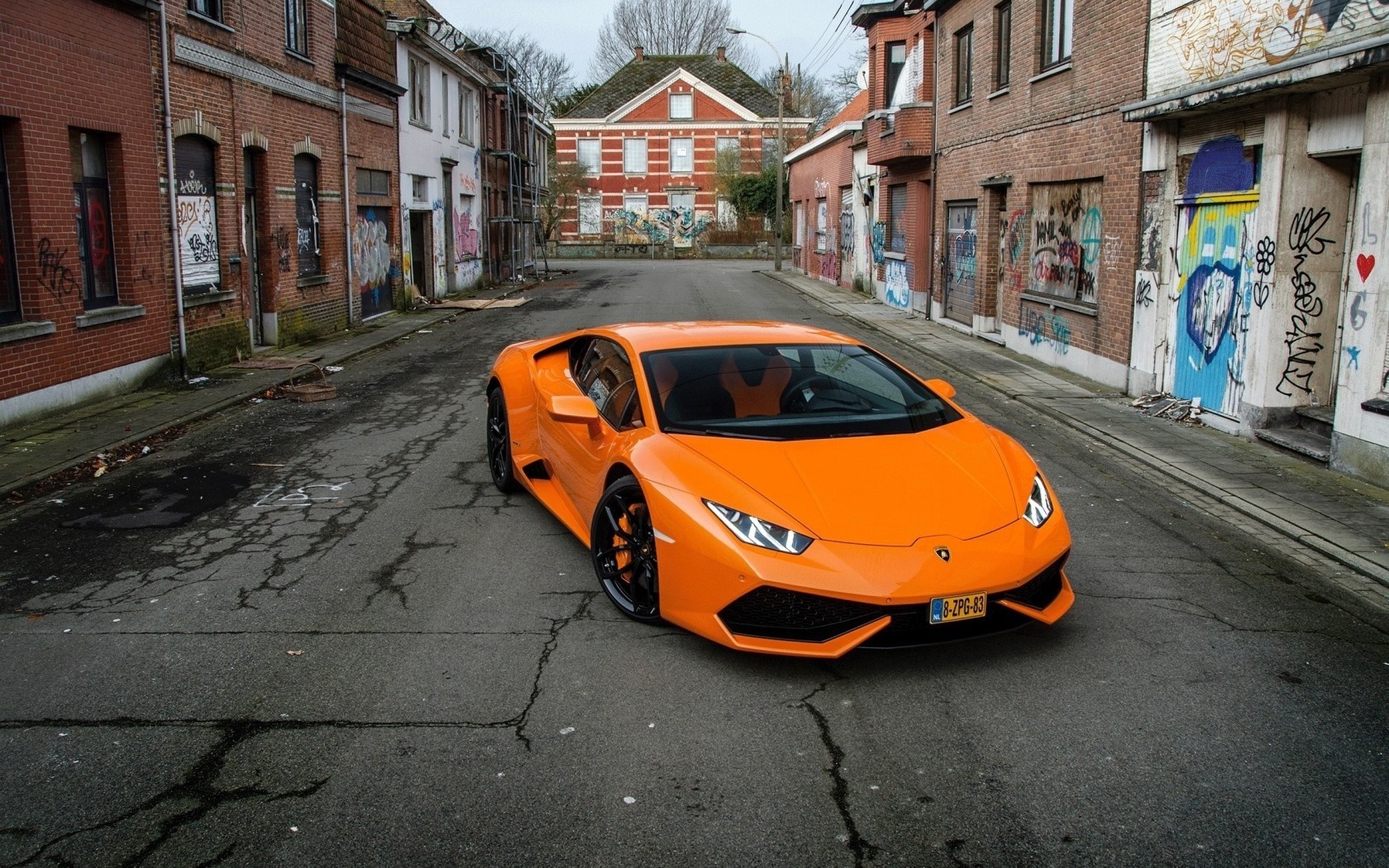Orange Lamborghini Huracan parked on a street with graffiti HD Wallpaper