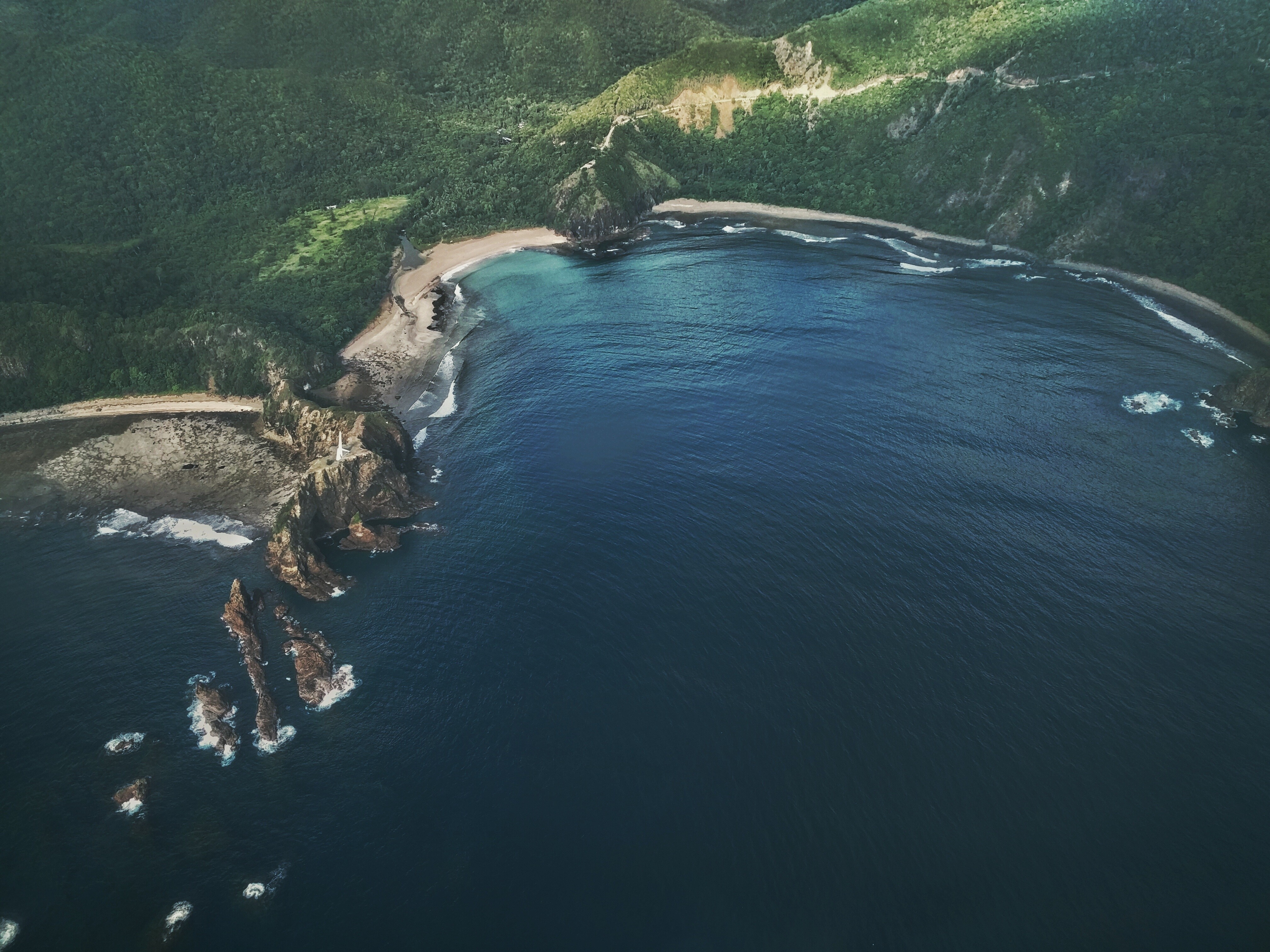 Aerial view of a rugged coastline with a bay and ocean HD Wallpaper