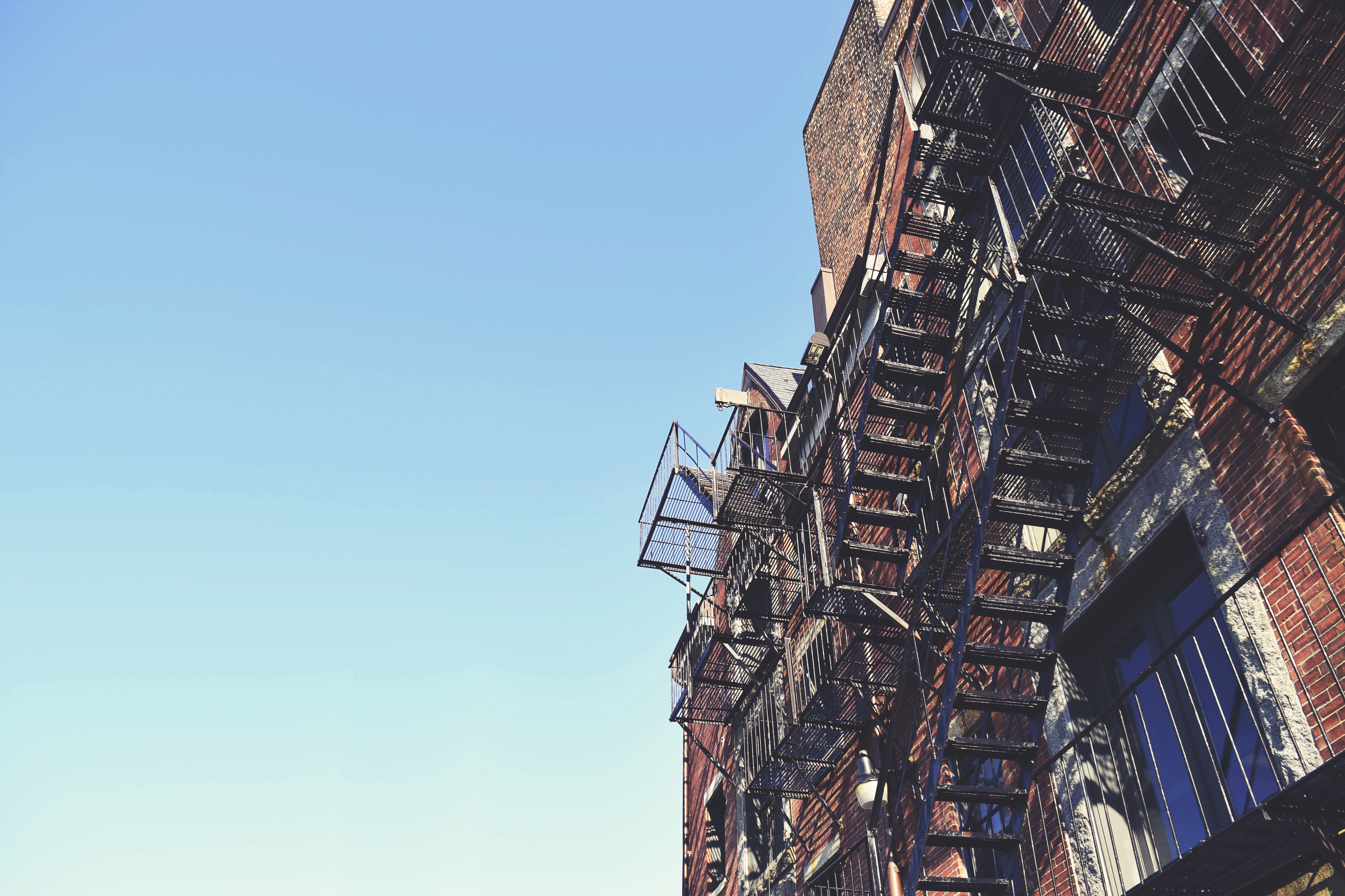Brick building with fire escapes against blue sky HD Wallpaper