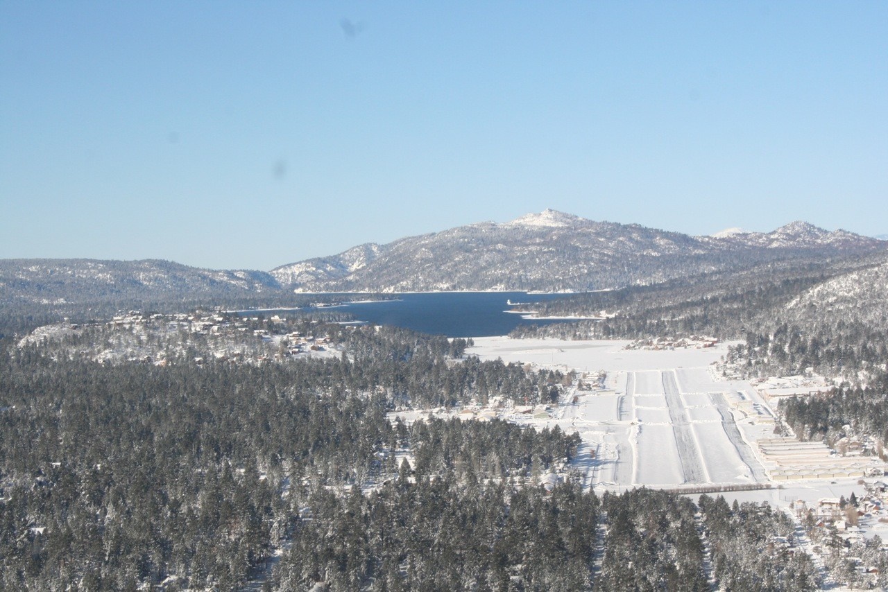 Aerial view of a snow-covered landscape with a lake and mountains HD Wallpaper