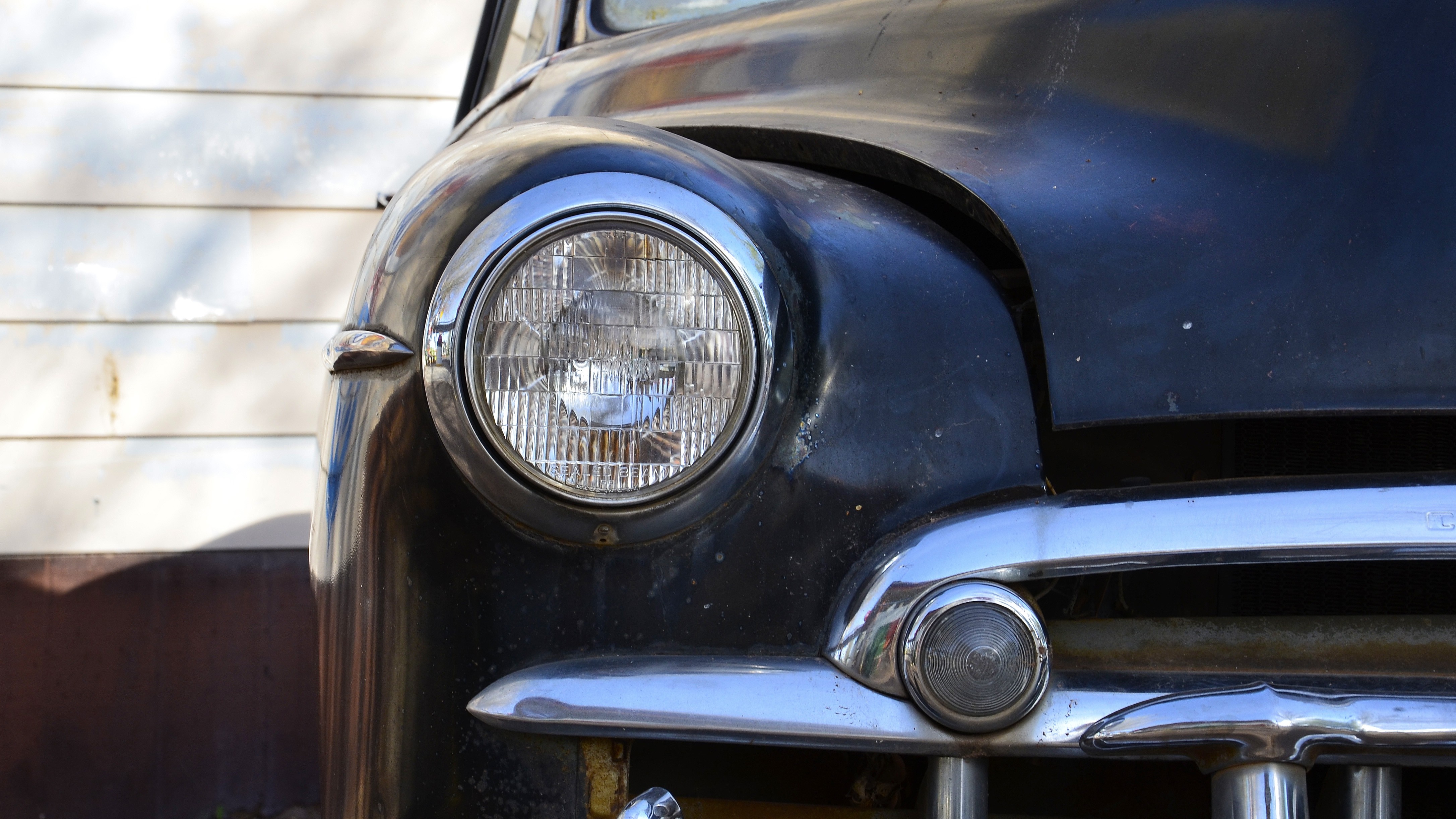 Close-up of a vintage black car headlight and bumper HD Wallpaper