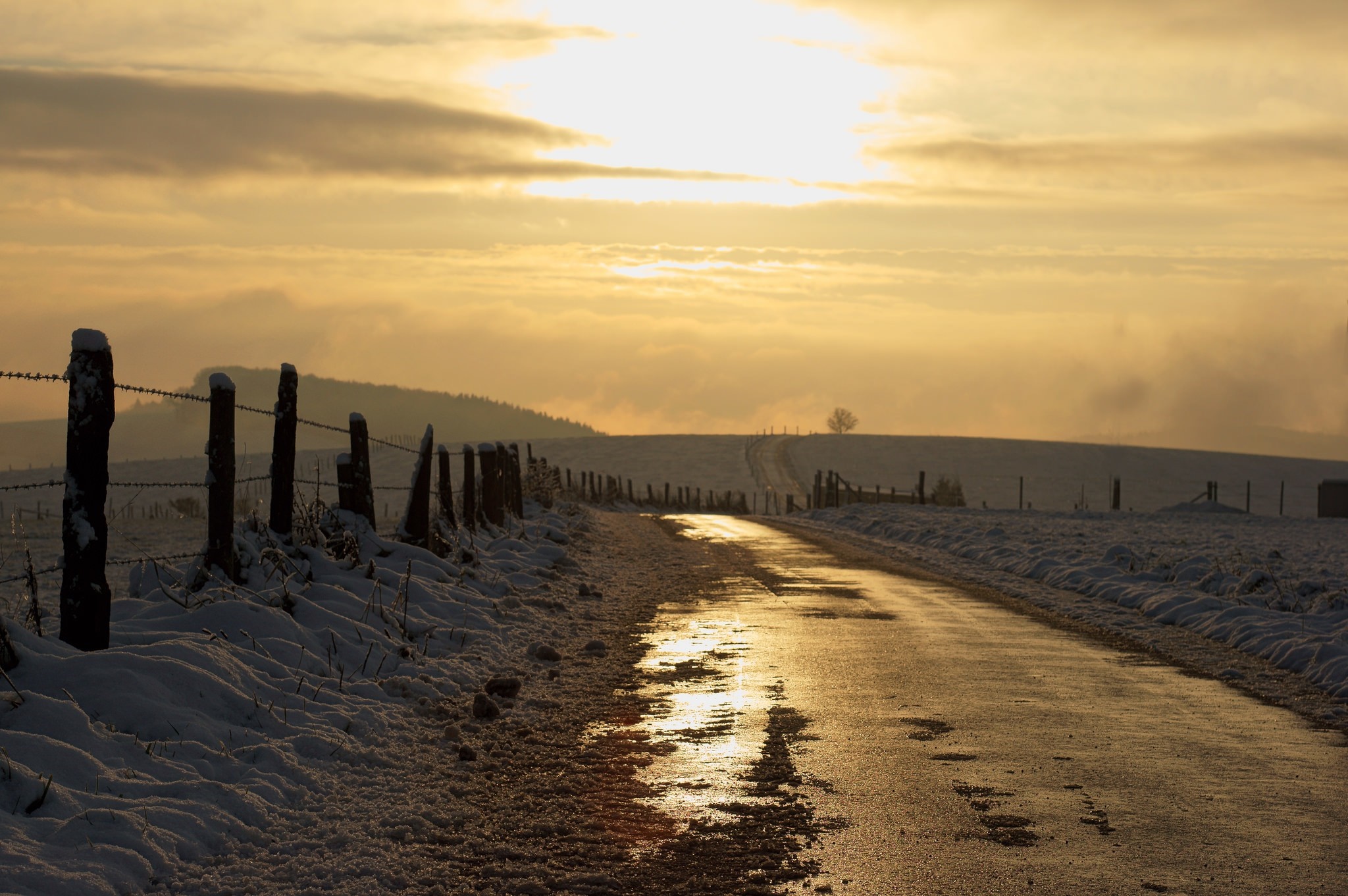 Winter road at sunset with snow and fence HD Wallpaper