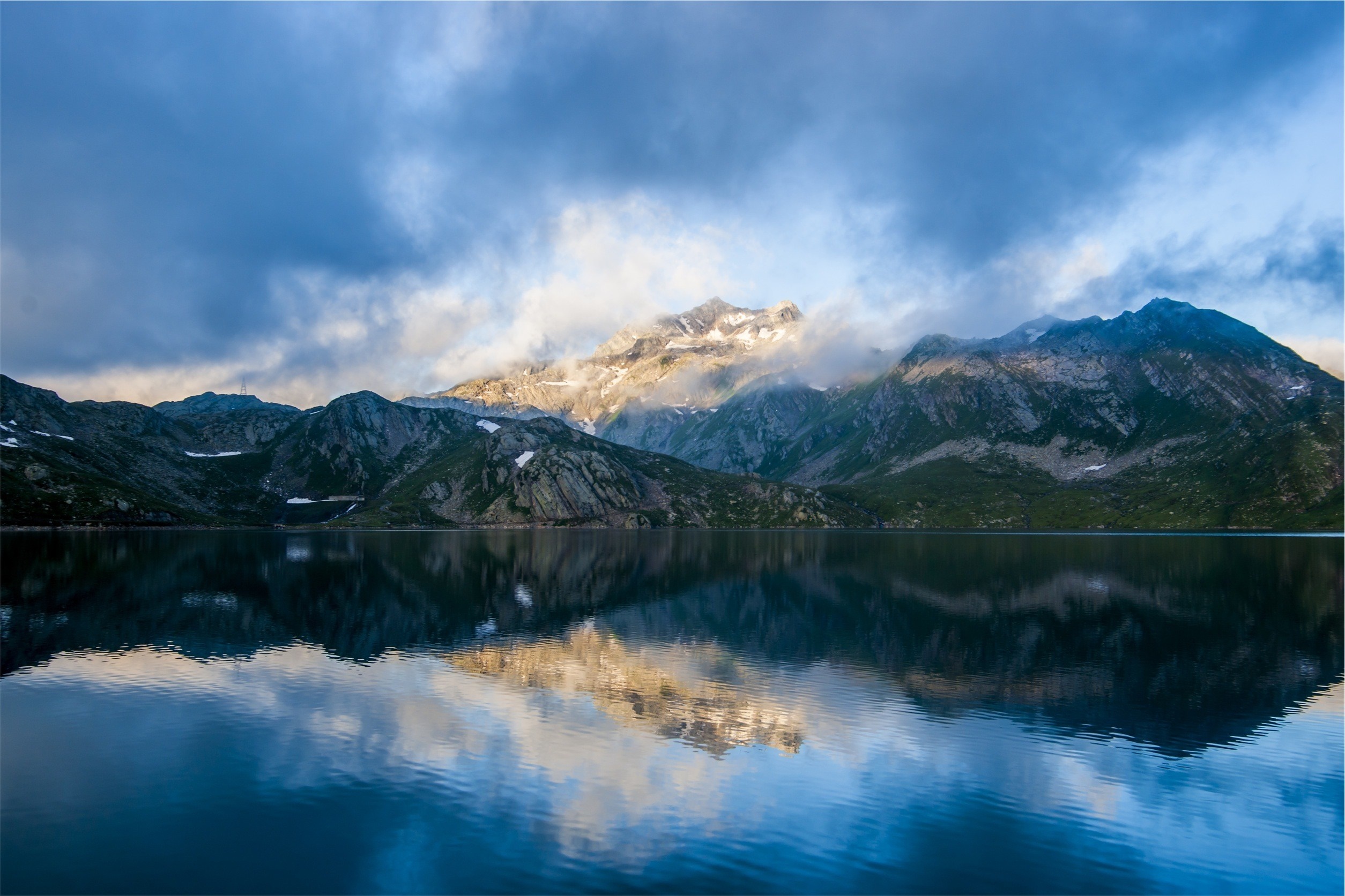 Mountain range reflected in a lake under cloudy sky HD Wallpaper