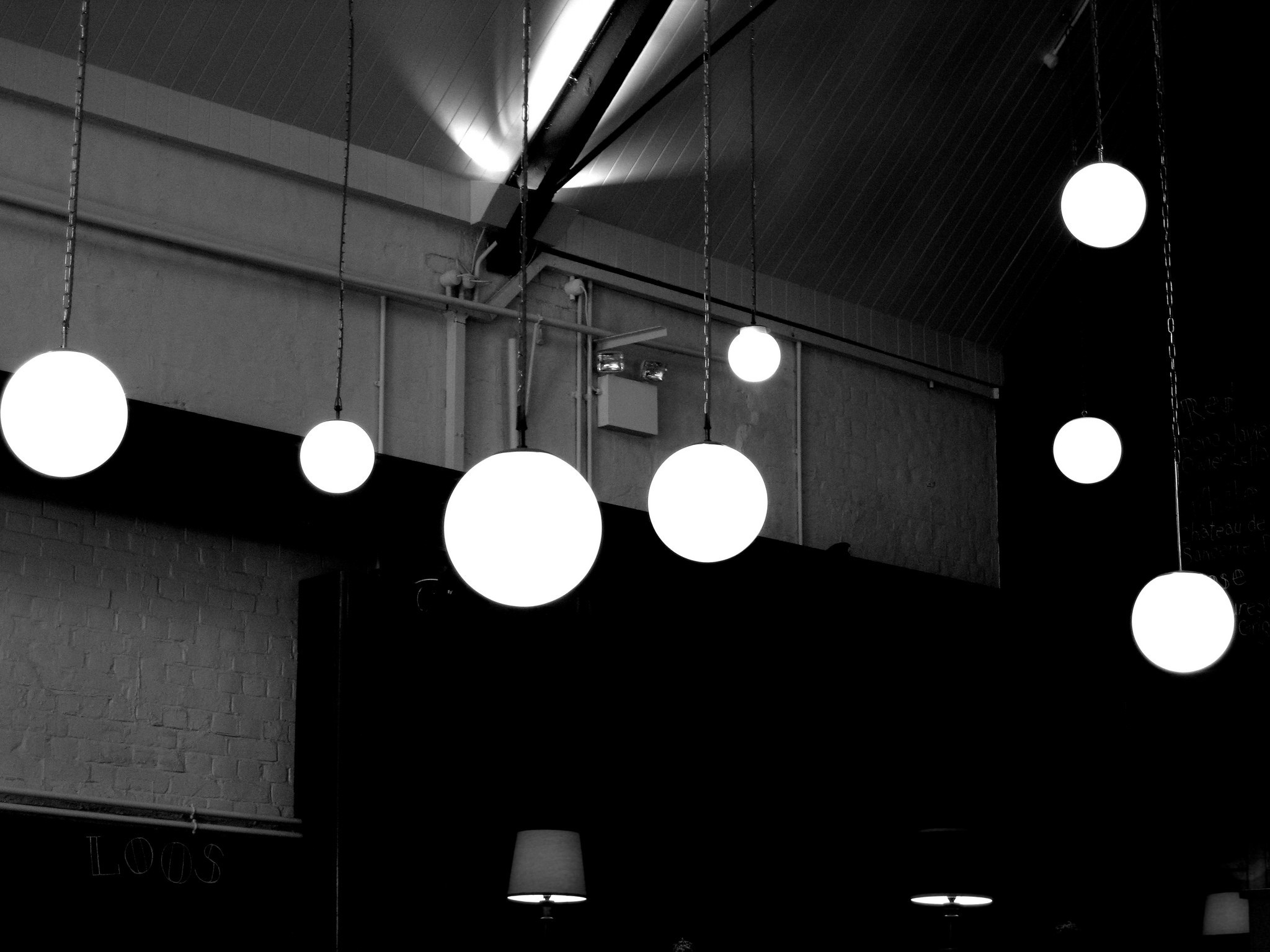 Monochrome image of spherical pendant lights hanging from a ceiling HD Wallpaper