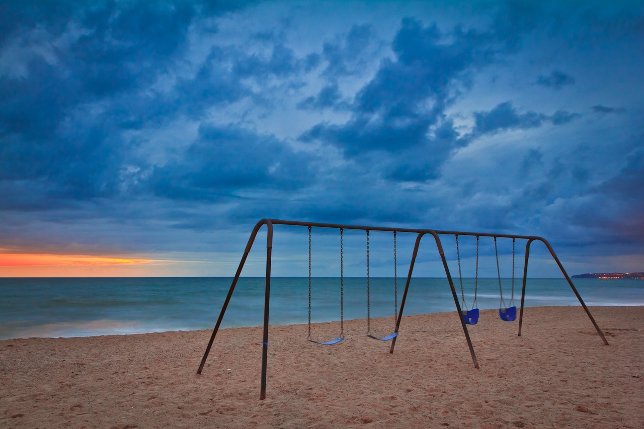 Swing set on a beach at dusk HD Wallpaper