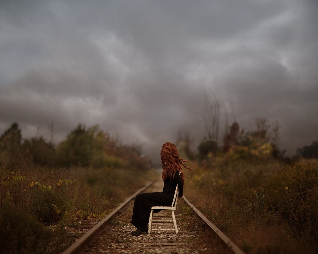Woman with red hair sitting on a chair on railroad tracks HD Wallpaper