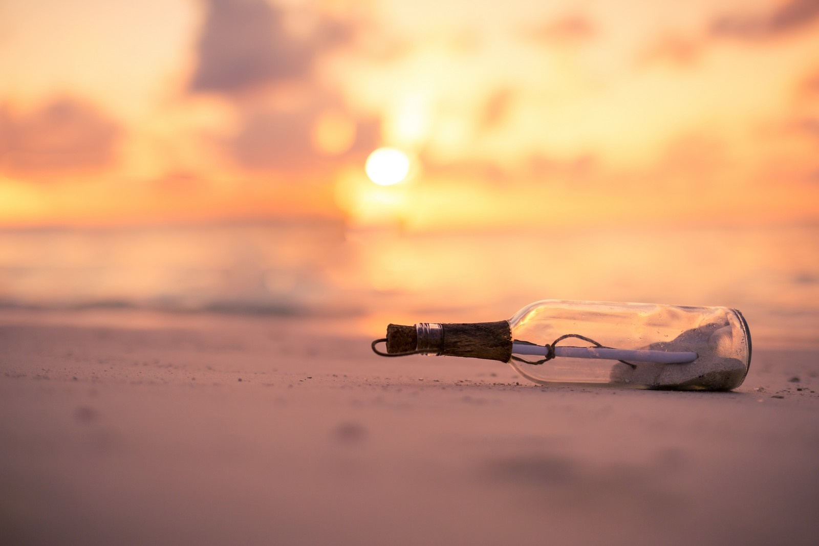 Message in a bottle on a beach at sunset HD Wallpaper