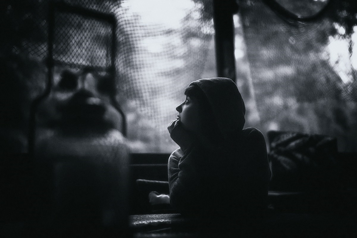 Monochrome photo of a person in a hoodie looking out a window HD Wallpaper