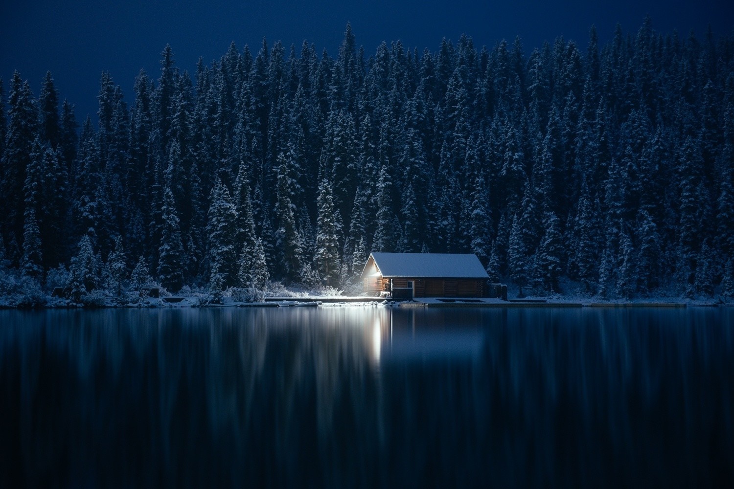 Cabin by a lake in a snowy forest at night HD Wallpaper