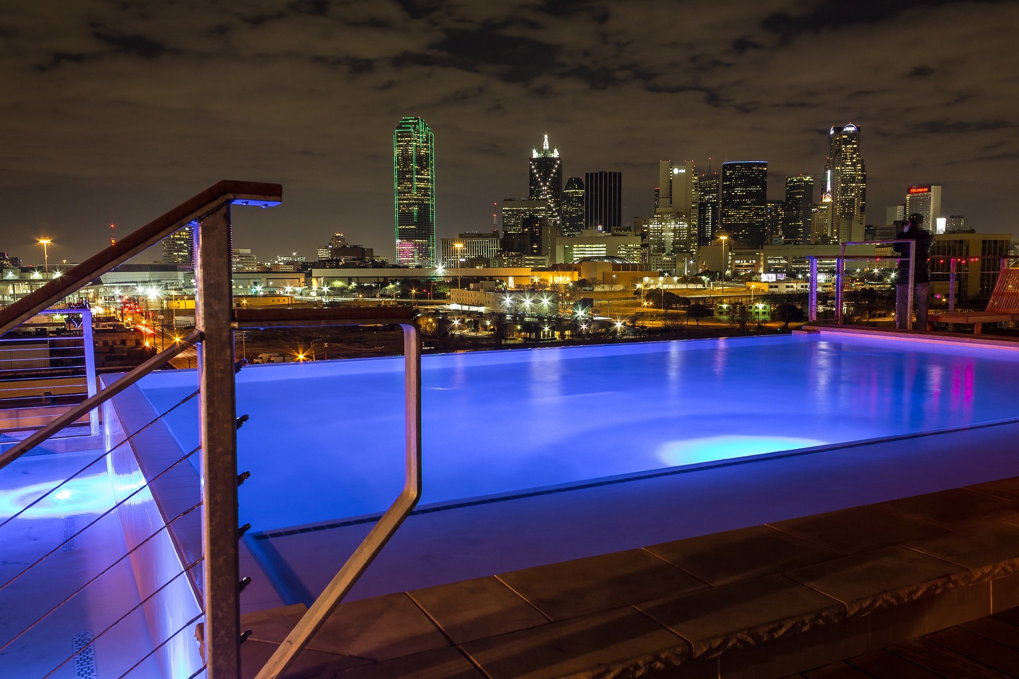 Infinity pool overlooking Dallas skyline at night HD Wallpaper
