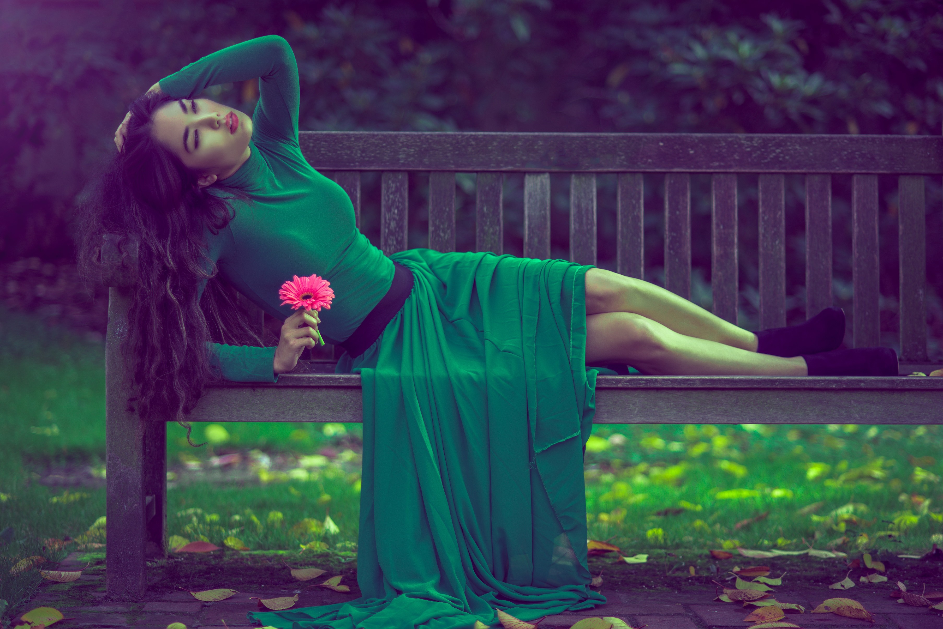 Woman in green dress holding a pink flower on a bench HD Wallpaper